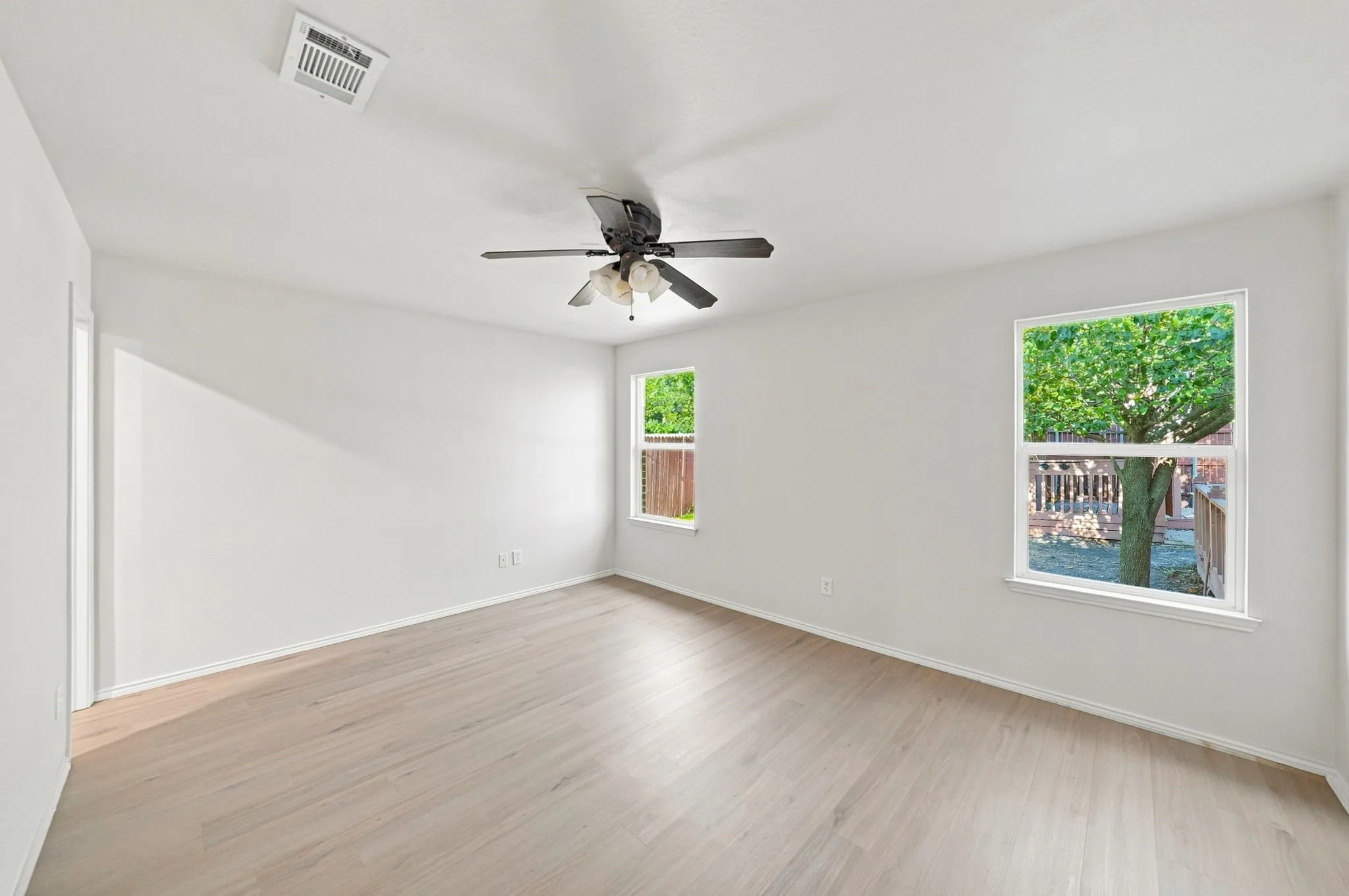 Spacious interior with neutral wall tones, wood-finish flooring, and multiple windows