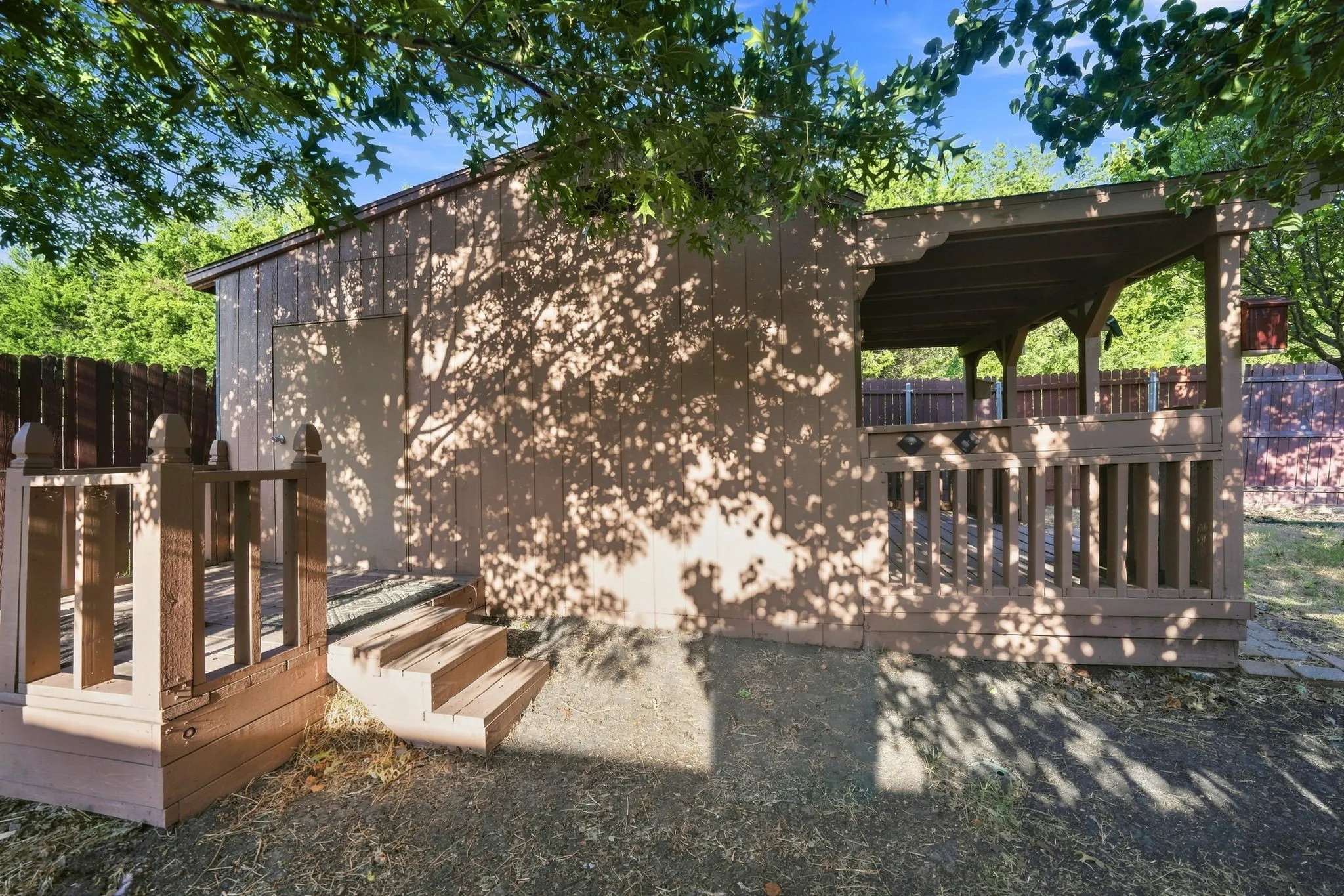 Detached structure featuring a covered porch, an open deck area, and wood panel siding