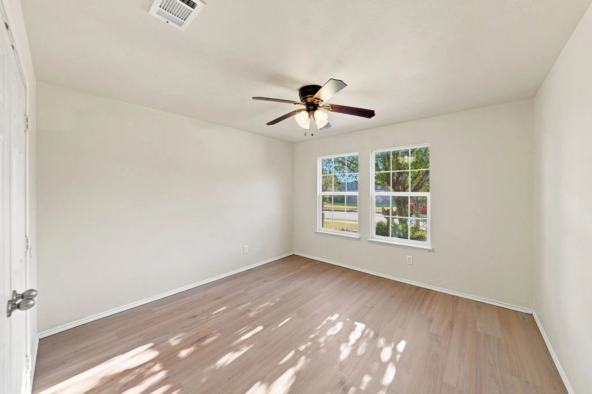 Wood-finish flooring, dual windows, ceiling fan with integrated lighting, and neutral wall paint