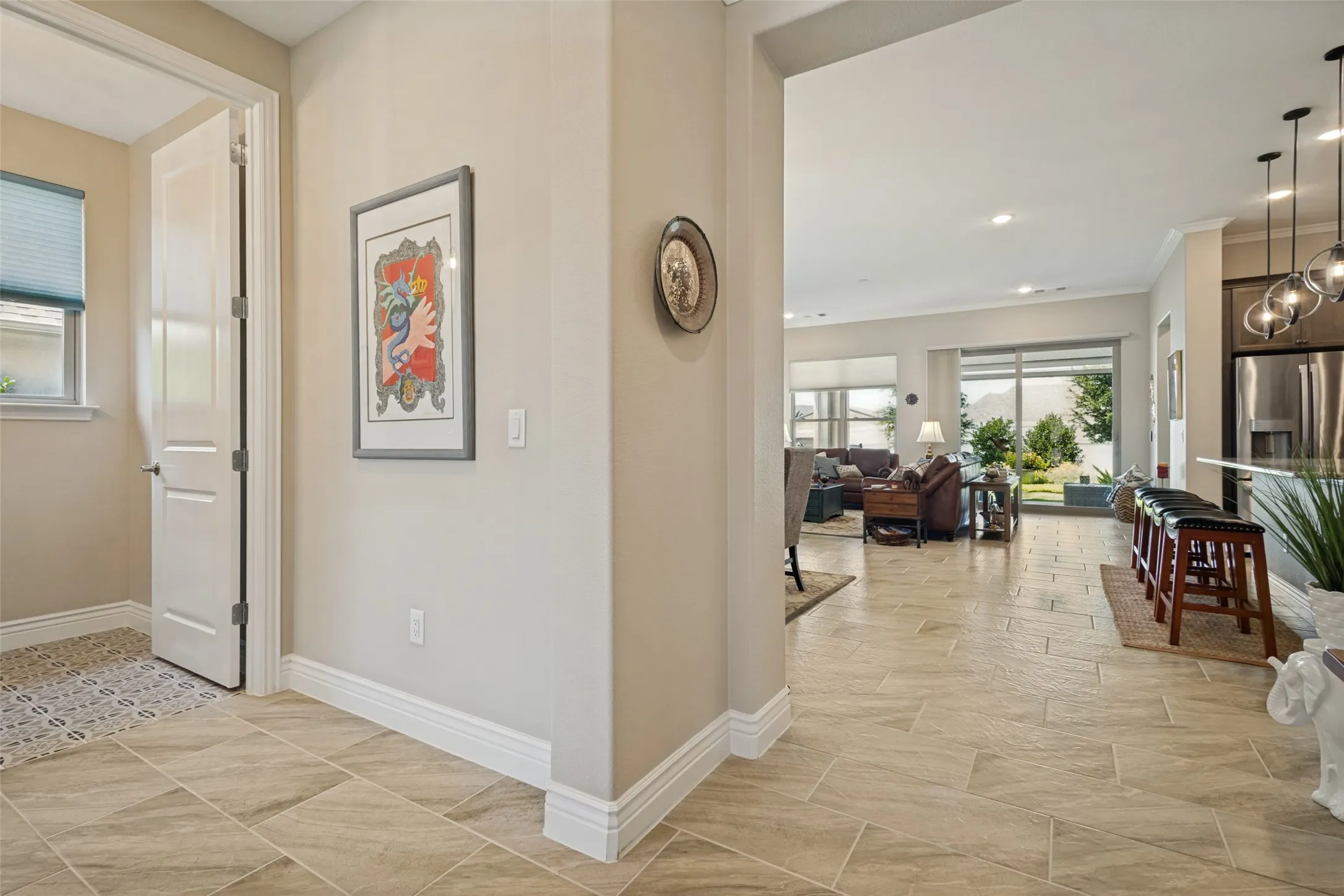 FROM THE ENTRY A GLANCE INTO THE LIVING AREA AND A HALF BATH IS ADJACENT AND FINISHED WITH FRAMED MIRROR, DESIGNER LIGHTING AND CERAMIC TILE IN A WHIMSICAL NEUTRAL PATTERN.