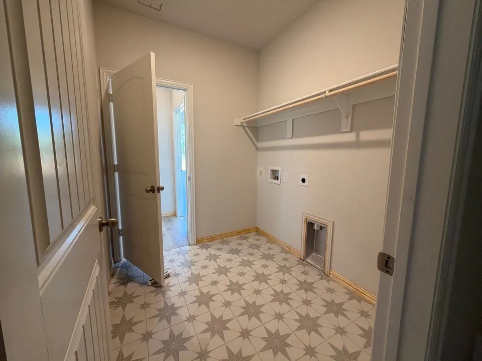 Laundry area featuring patterned tile flooring, built-in shelving, and light-colored walls