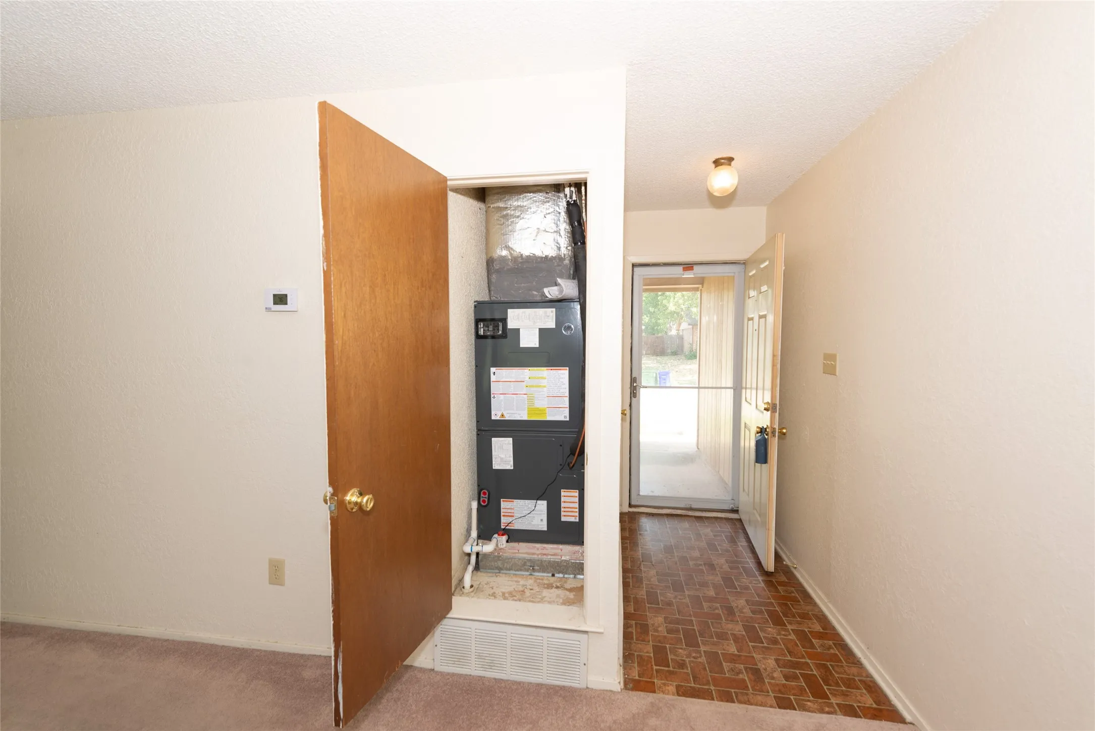 Entrance with a ceramic tile-patterned flooring, ceiling-mounted light fixture, and a white entry door with a screen door