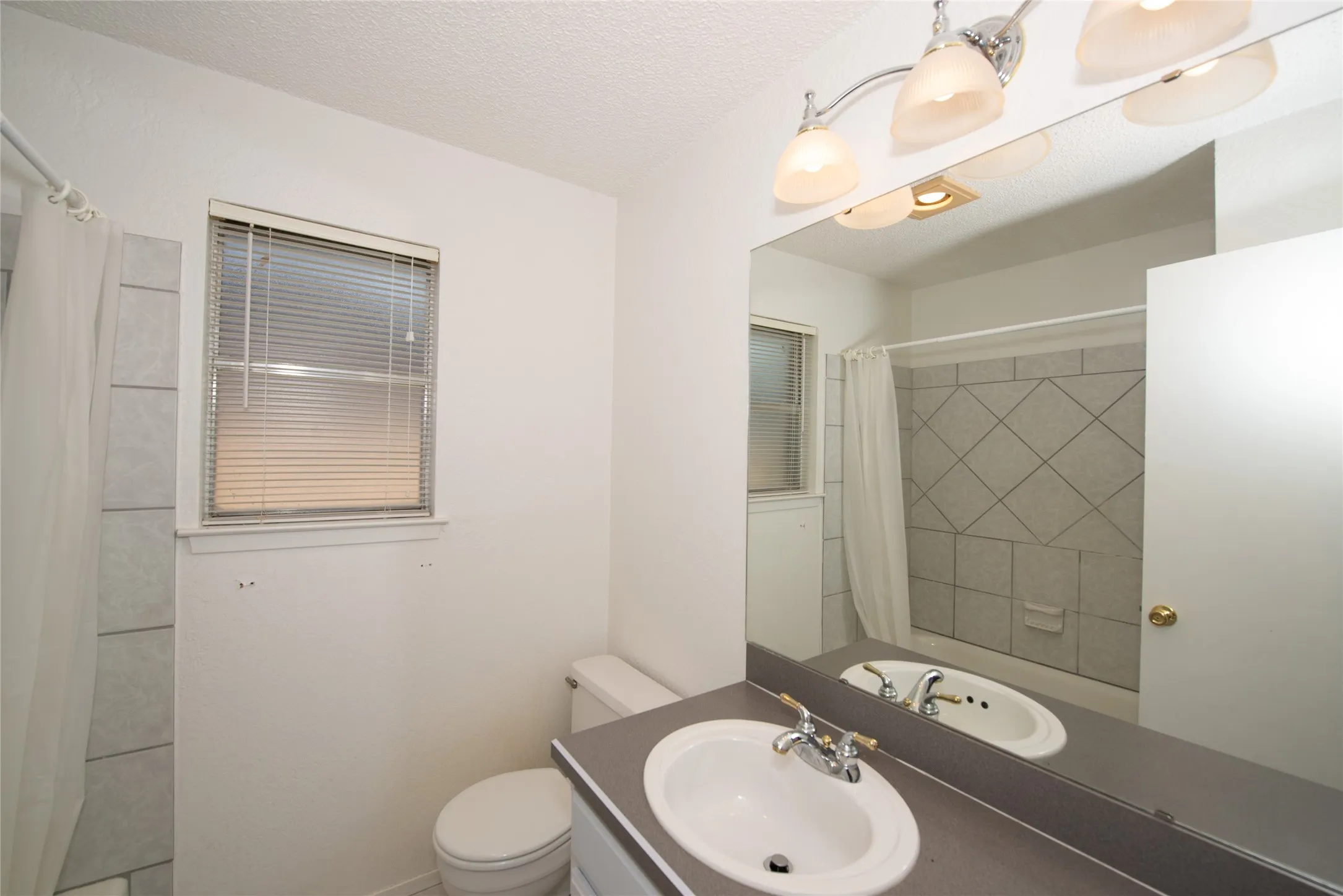 White vanity with a single basin sink, chrome faucet, and gray countertop