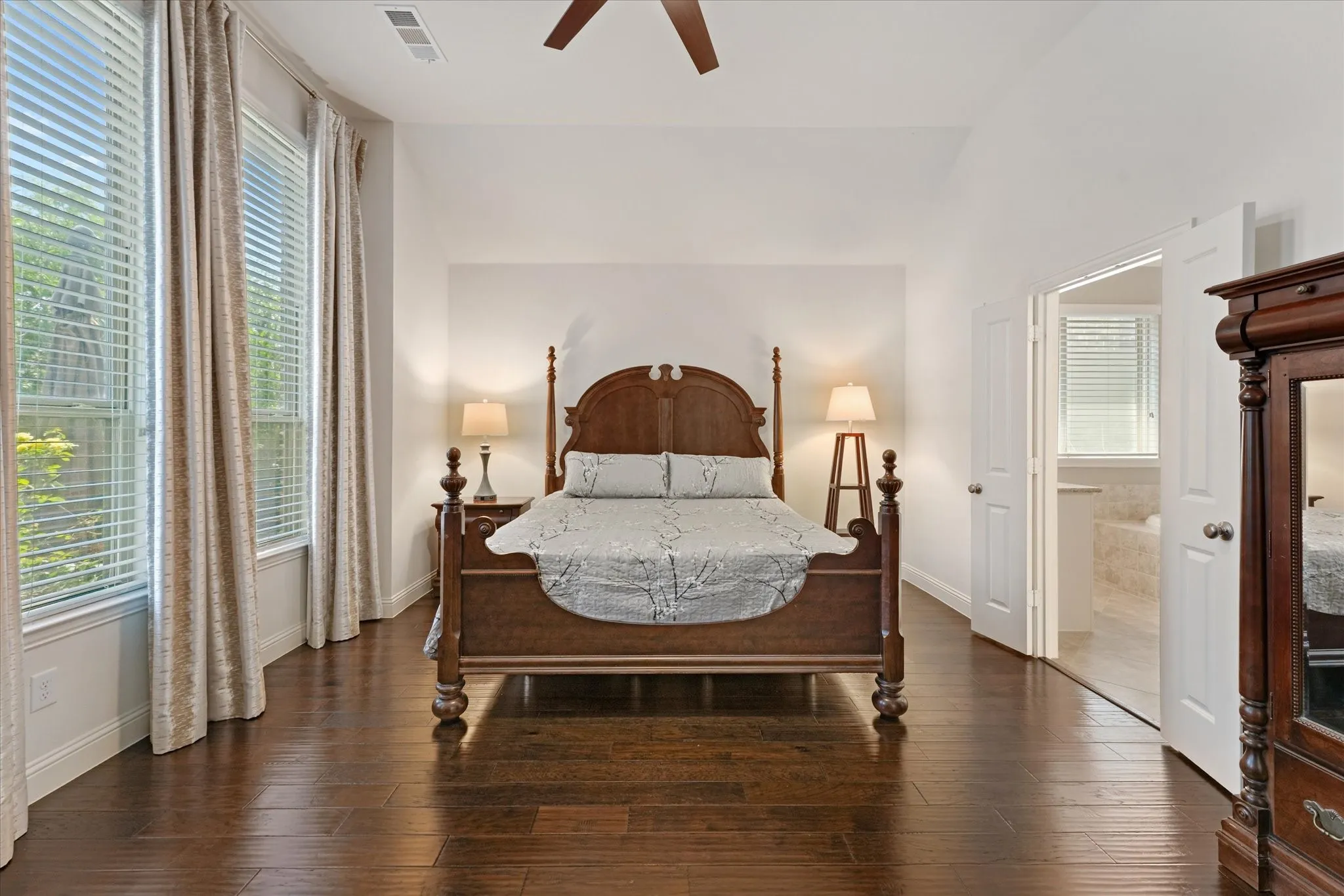 Spacious primary suite with vaulted ceilings, engineered hardwood flooring, large windows and direct access to the ensuite bath.