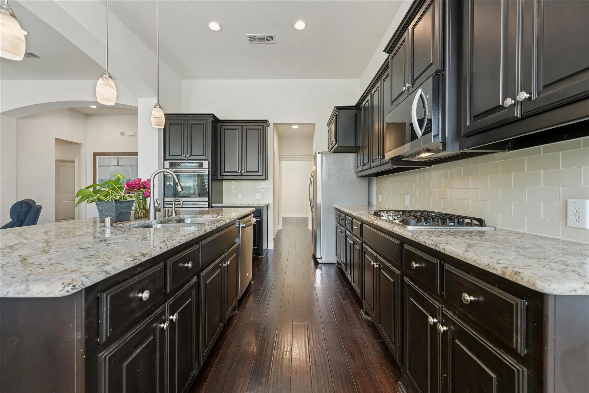 Spacious kitchen with granite countertops, gas cooktop, subway tile backsplash, stainless steel appliances and abundant cabinet storage.