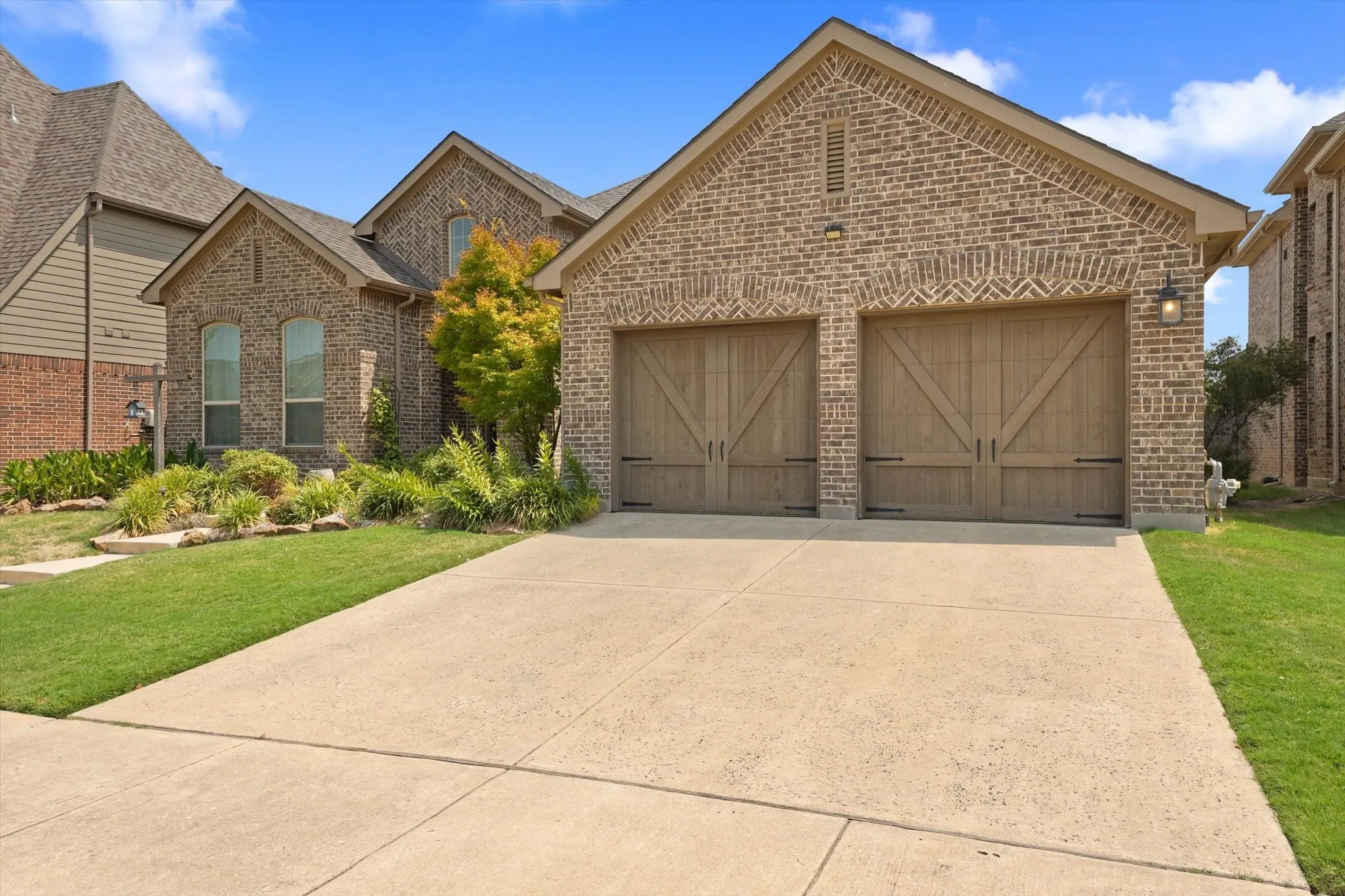 Three-car garage with separate garage doors and wide driveway, providing additional parking, storage or workspace in this Harvest home.