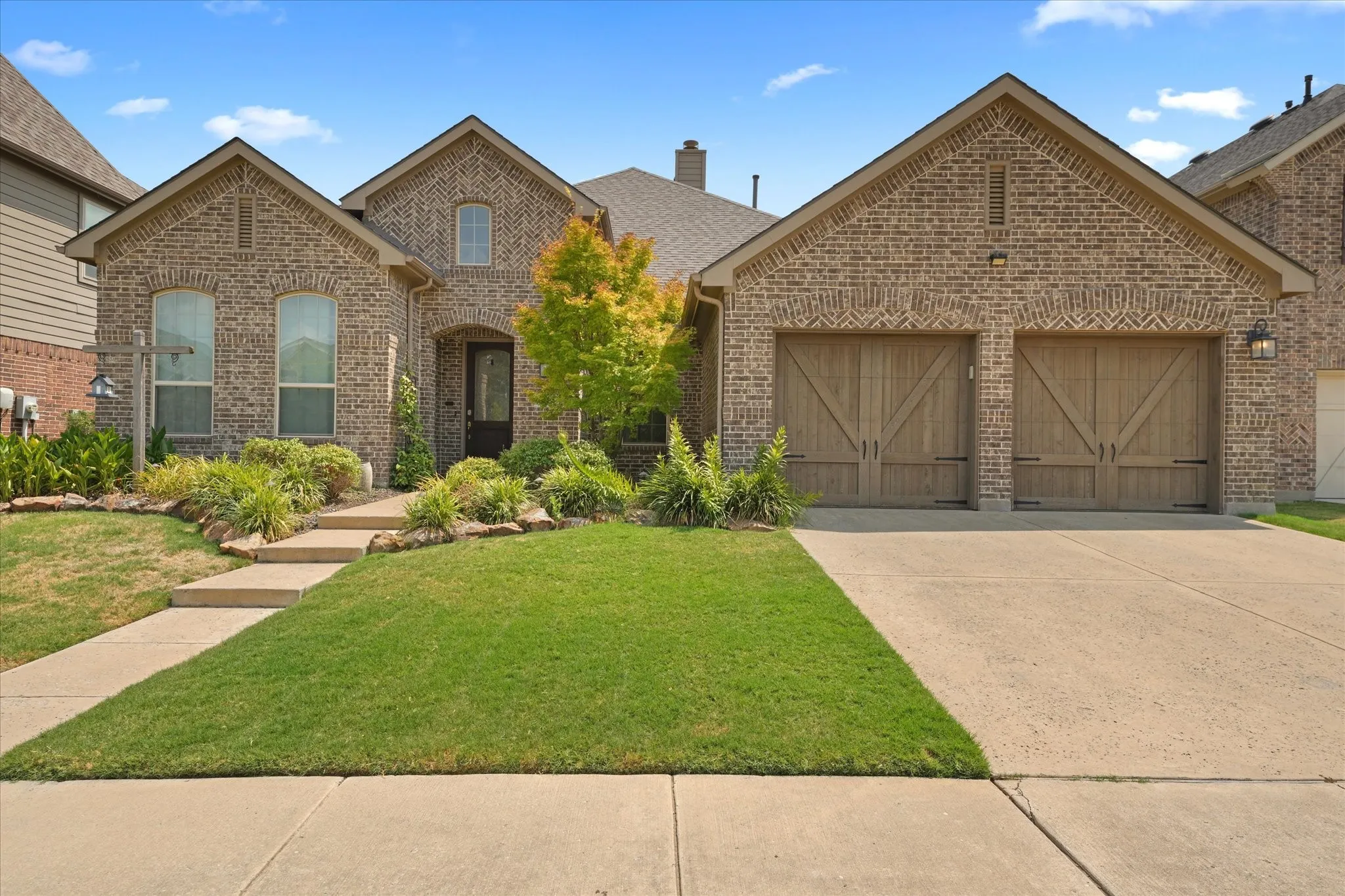 Front view of the 3-bedroom, 2-bath home with established landscaping, traditional brick architecture and a single-story floor plan in Argyle ISD.