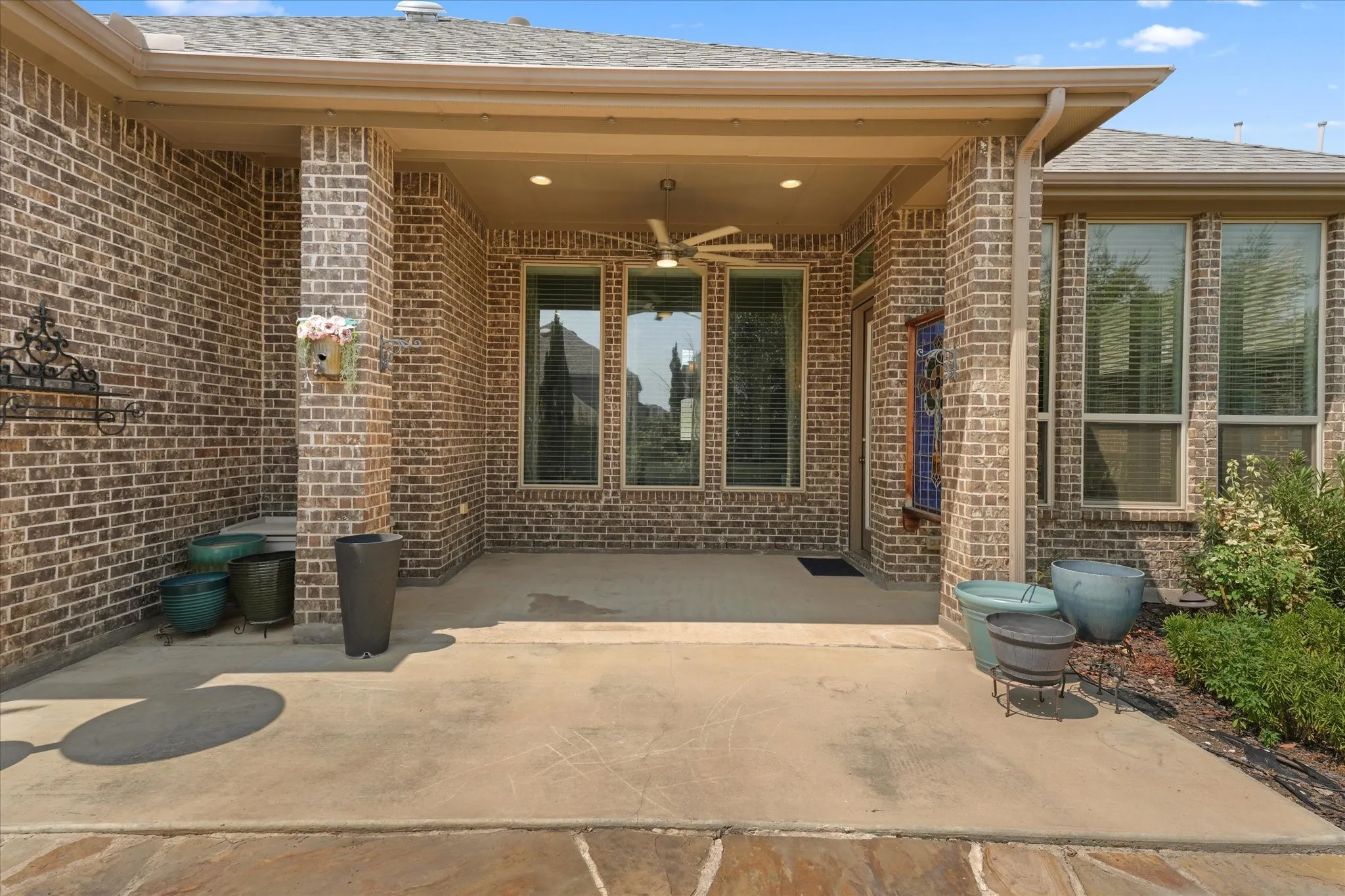 Spacious covered patio with room for outdoor dining and seating, ideal for relaxing or entertaining year-round.