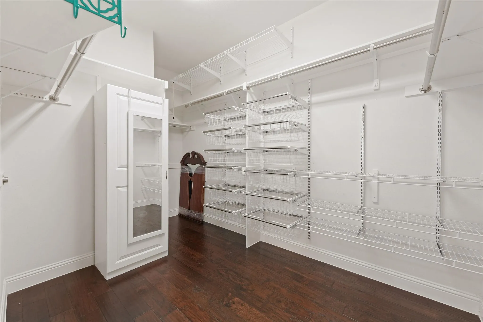Large walk-in closet with custom organization system, built-in drawers, shelving and abundant hanging space.