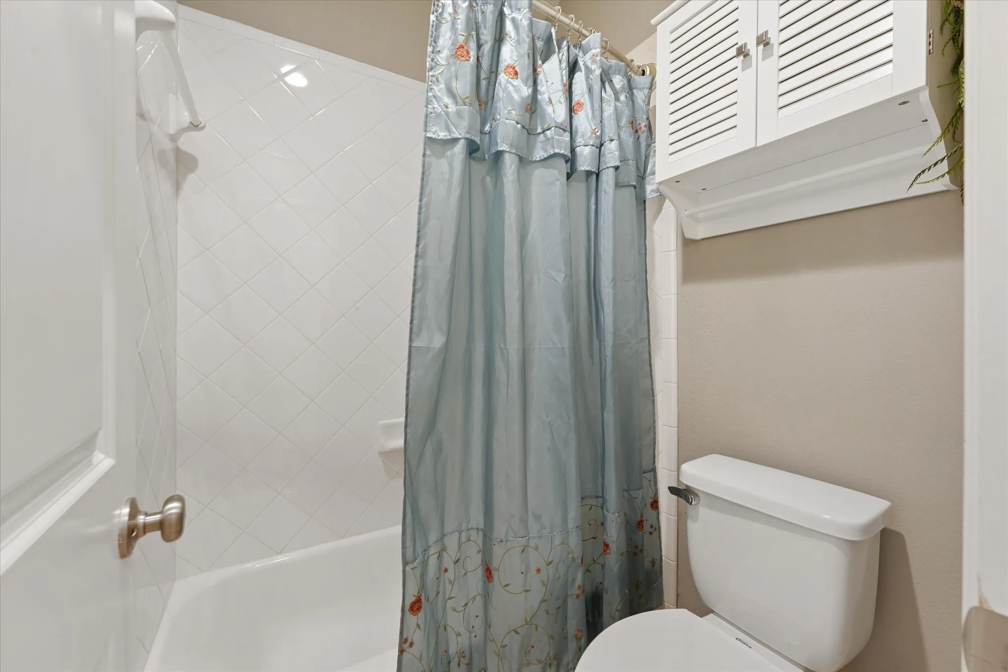 Secondary bathroom with tiled tub and shower combination, built-in storage and neutral finishes.