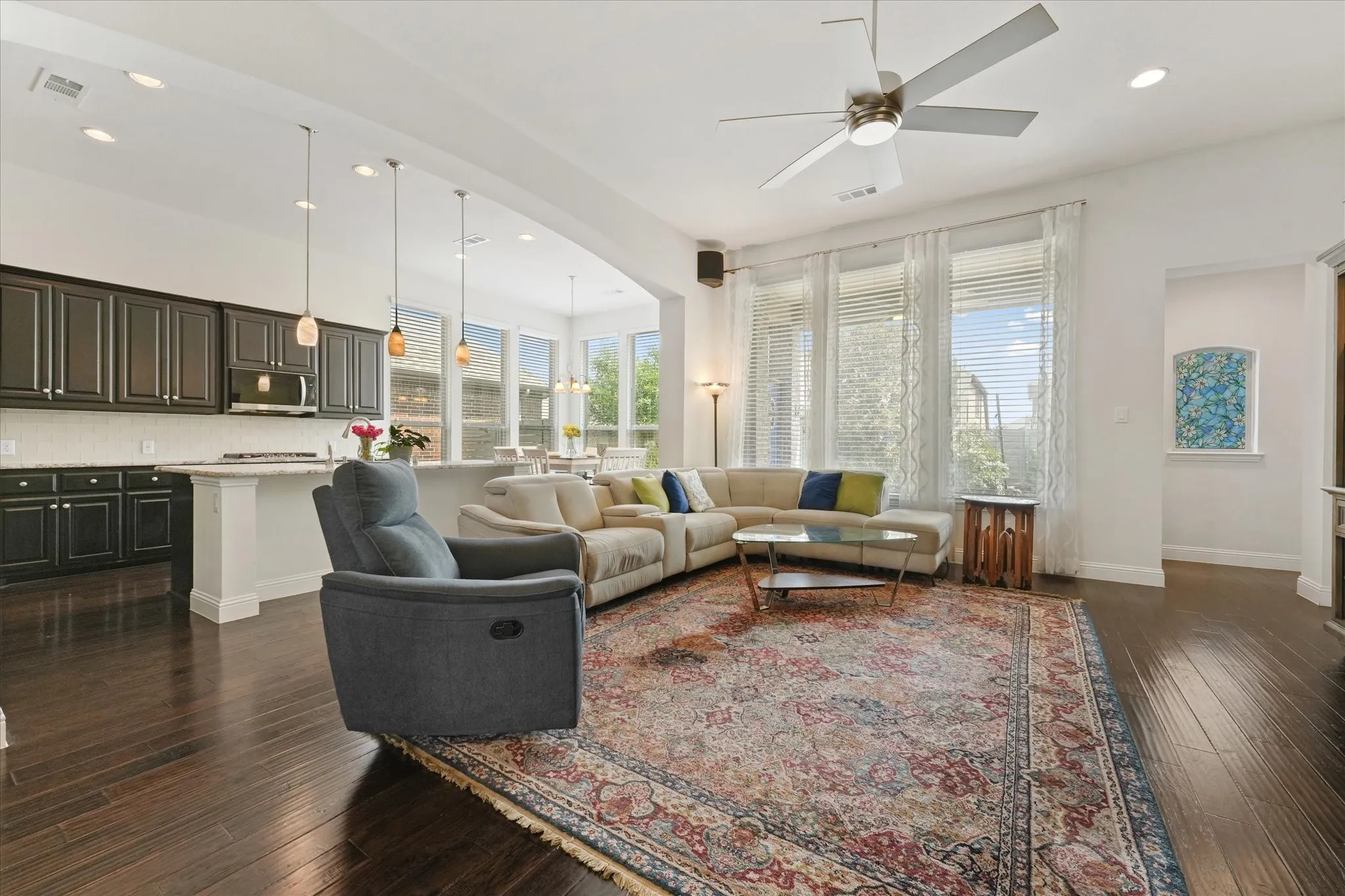 Light-filled living area with tall windows, open sightlines to the kitchen and breakfast area, and no carpet throughout the home.