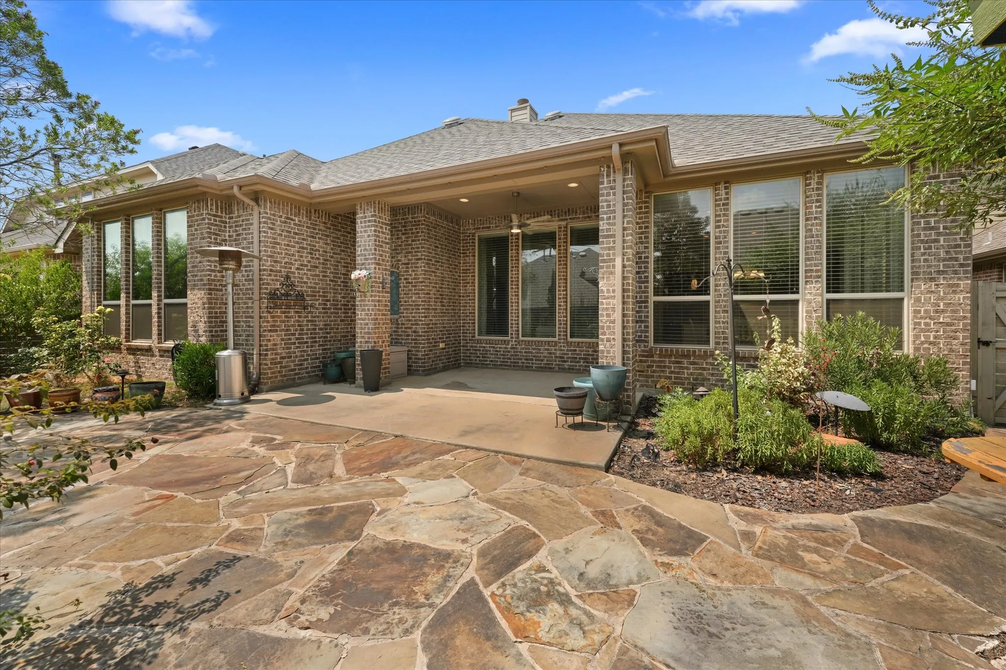 Covered back patio with ceiling fan and recessed lighting, offering a comfortable outdoor living space overlooking the landscaped backyard.