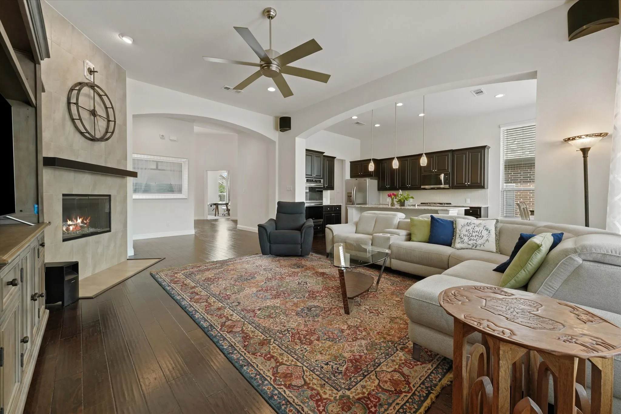 Spacious family room with a gas fireplace, built-in sound system speakers, hardwood flooring and an open connection to the kitchen.