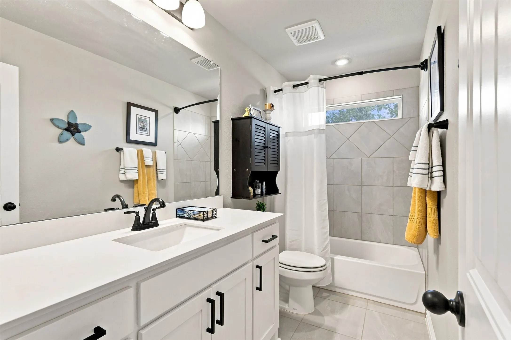 Spa-inspired bathroom featuring a white vanity with dual sinks, quartz countertop, and matte black hardware