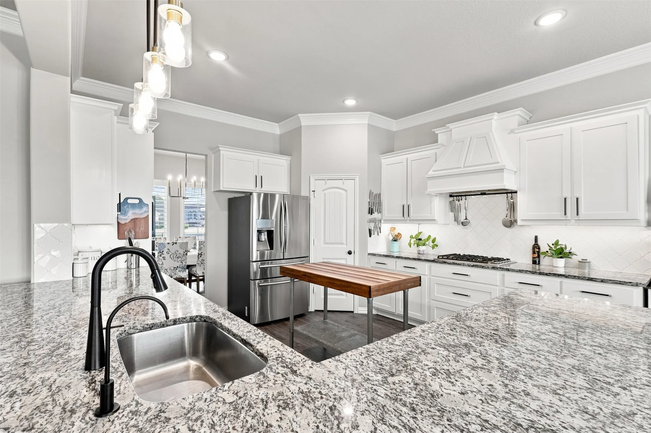 Kitchen featuring granite countertops, white cabinetry, a built-in stainless steel refrigerator, and a stainless steel sink with a matte black faucet