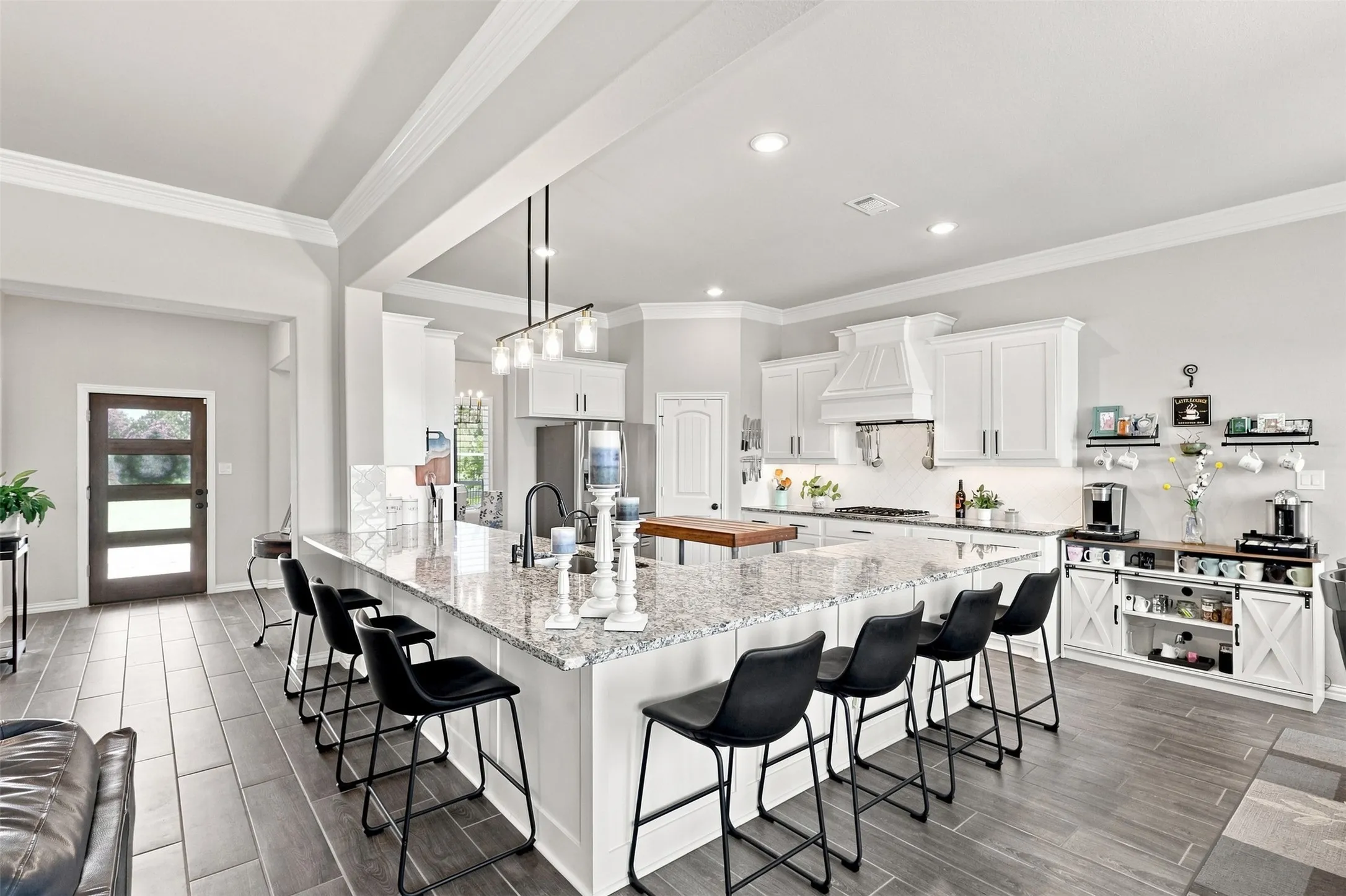 Gourmet kitchen featuring white cabinetry, stainless steel appliances, and a large center island with seating for multiple guests