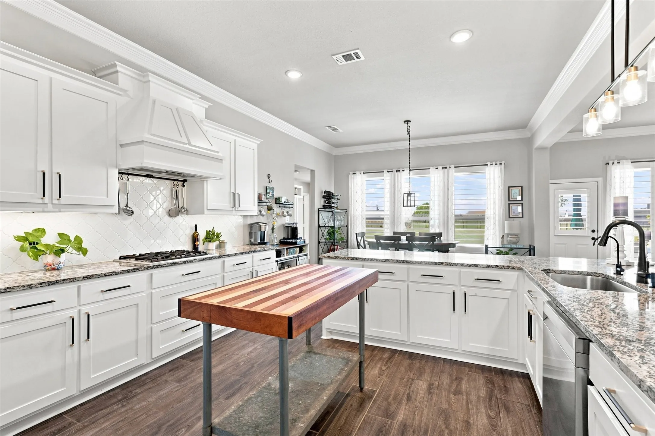 White shaker cabinetry, wood-finish flooring, granite countertops, decorative tile backsplash, and a built-in gas range