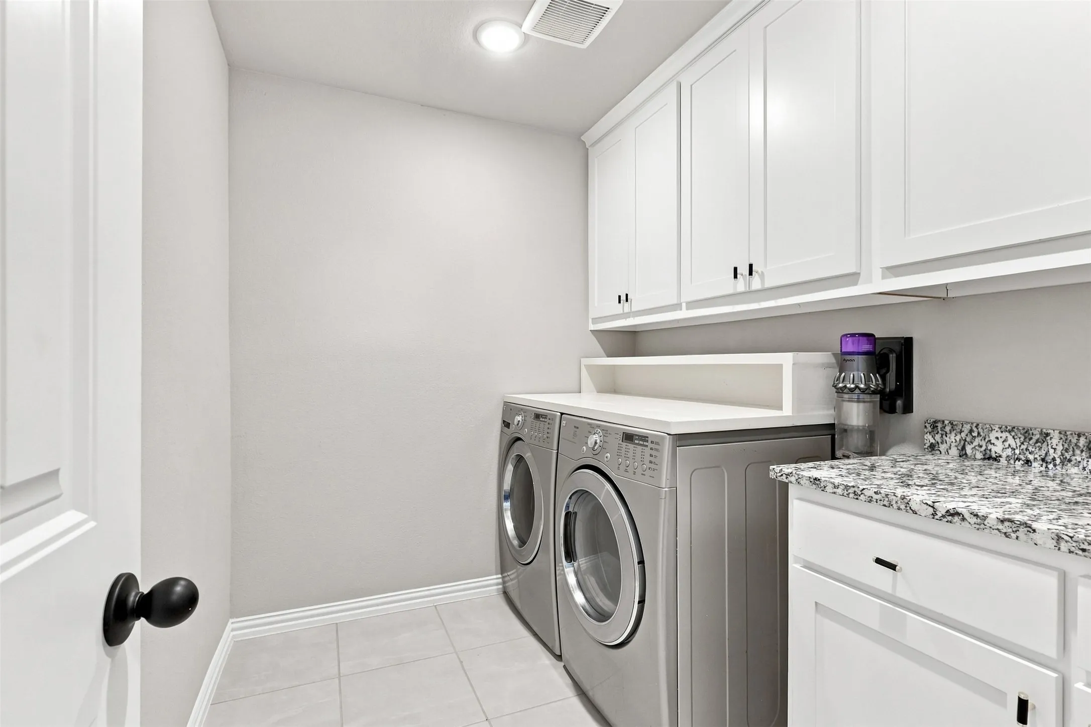 Laundry room featuring white cabinetry, a light-toned countertop, and tile flooring
