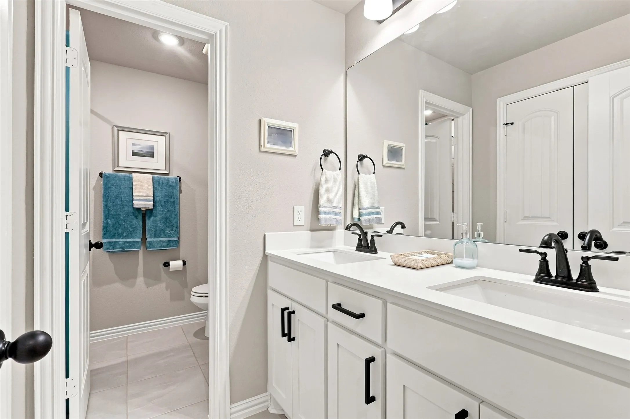 Dual vanity with white cabinetry, white countertops, and matte black fixtures