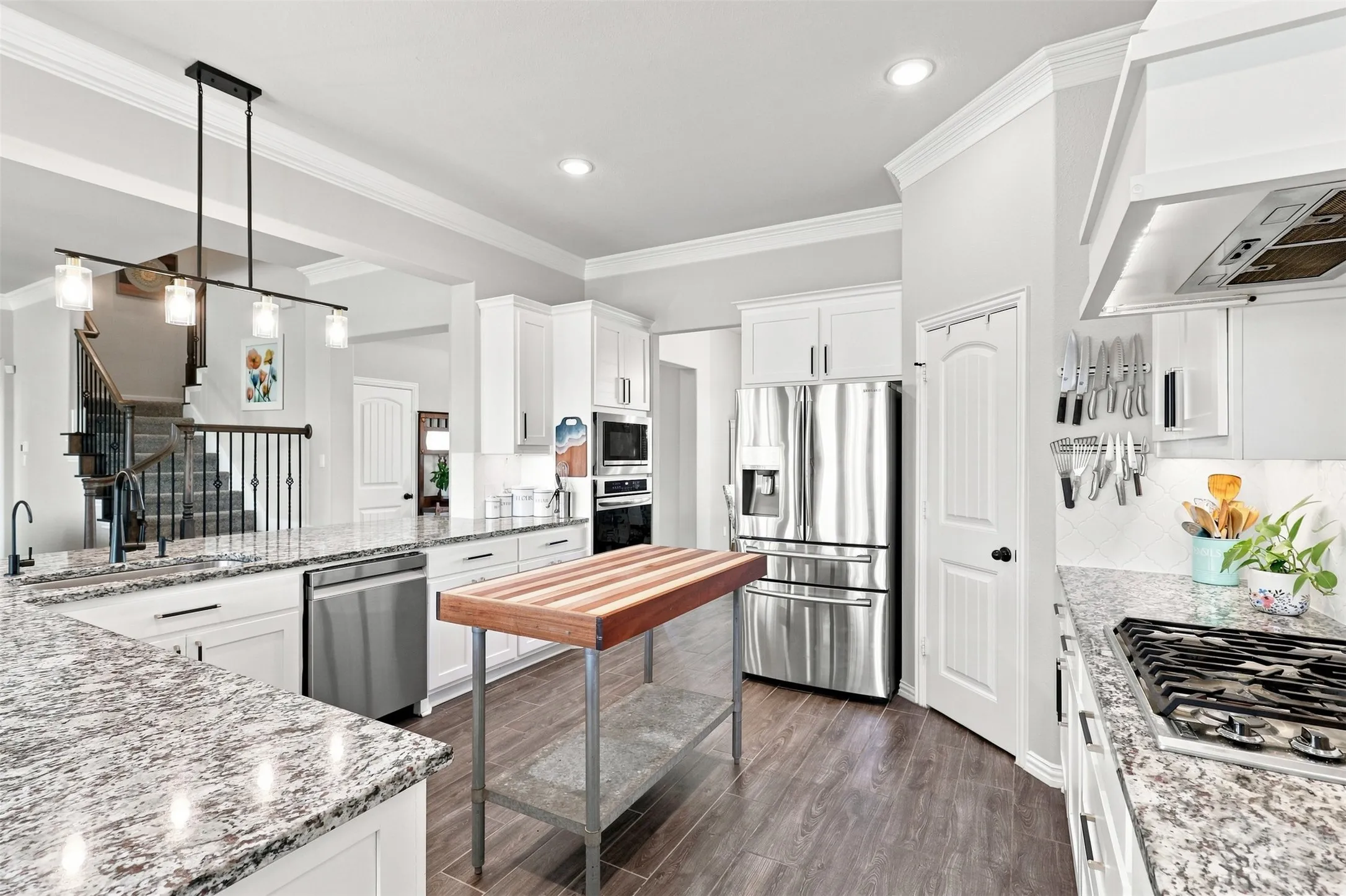 Kitchen featuring stone countertops, stainless steel appliances, wood-finish flooring, white cabinetry, and a gas range