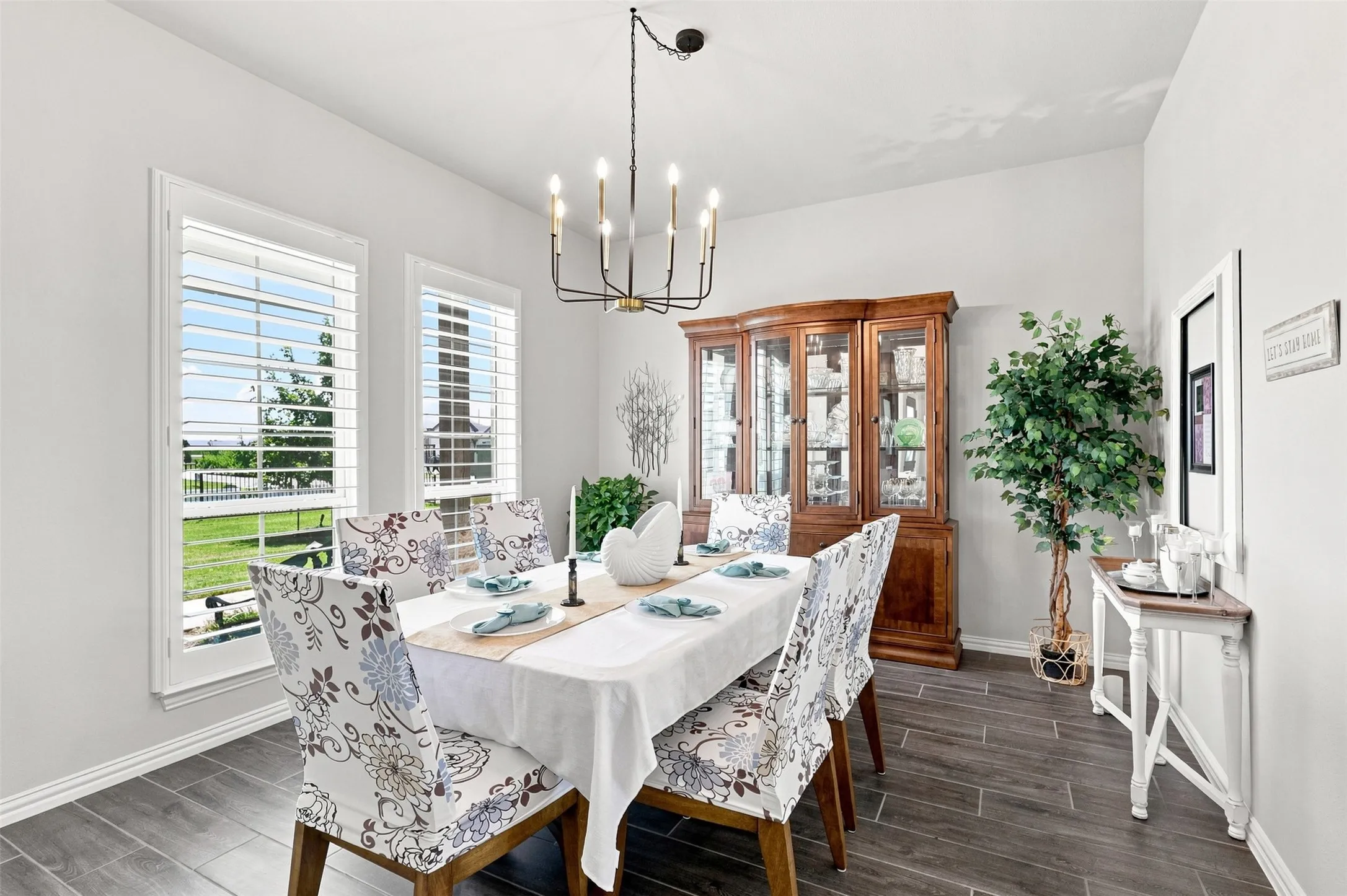 Dining space featuring wood-look tile flooring, white walls, and a black and brass chandelier