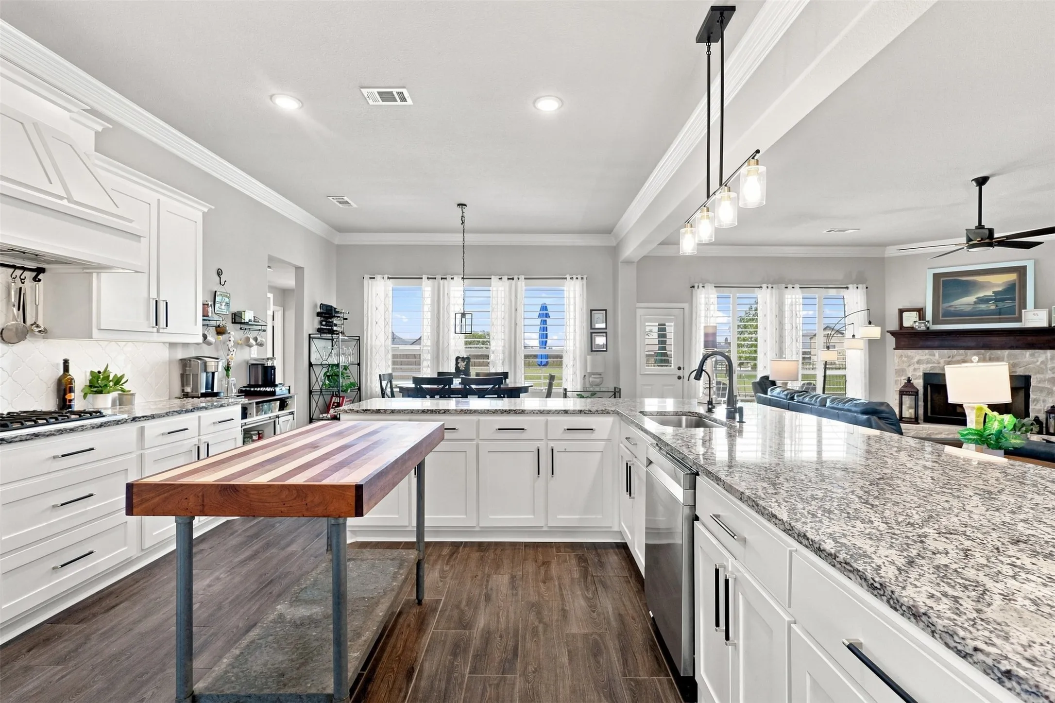 Gourmet kitchen featuring white cabinetry, stone countertops, wood-finish flooring, a built-in cooktop with a range hood, and recessed lighting