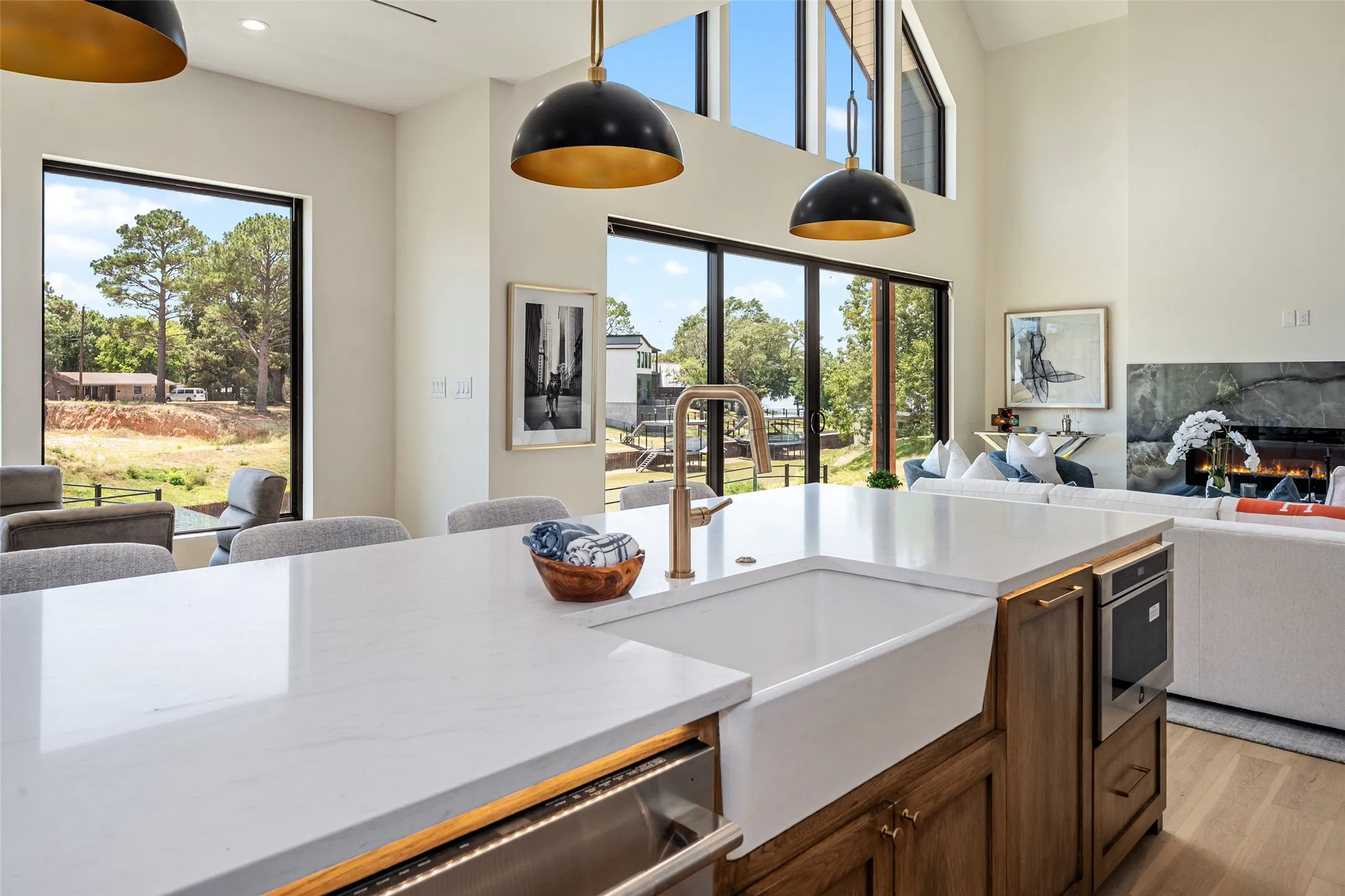 Kitchen island with a white farmhouse sink, brass faucet, and built-in microwave