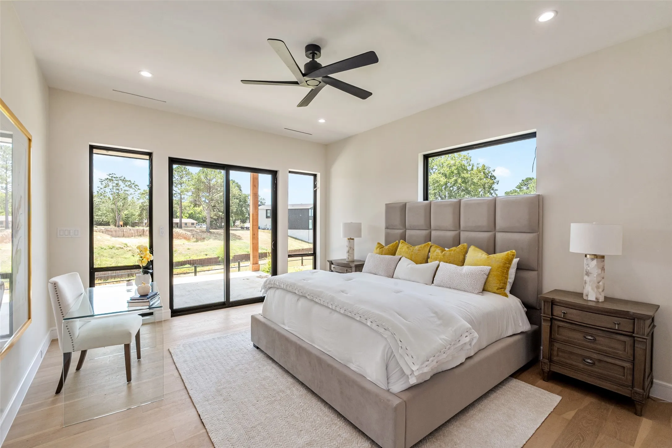 Recessed lighting, wood-finish flooring, a contemporary ceiling fan, and black-framed windows with sliding glass doors
