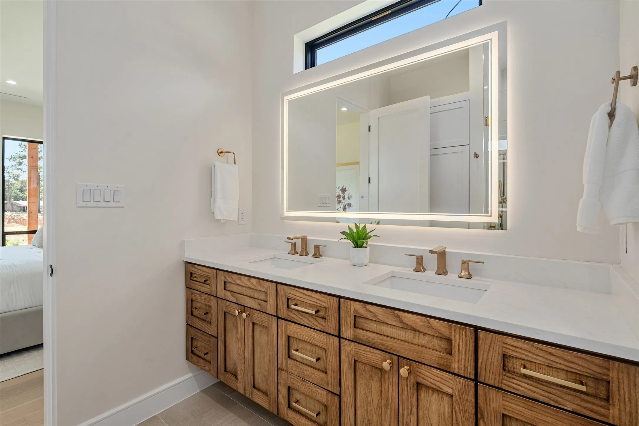 Dual vanity with wood-finish cabinetry, white stone countertops, and undermount sinks