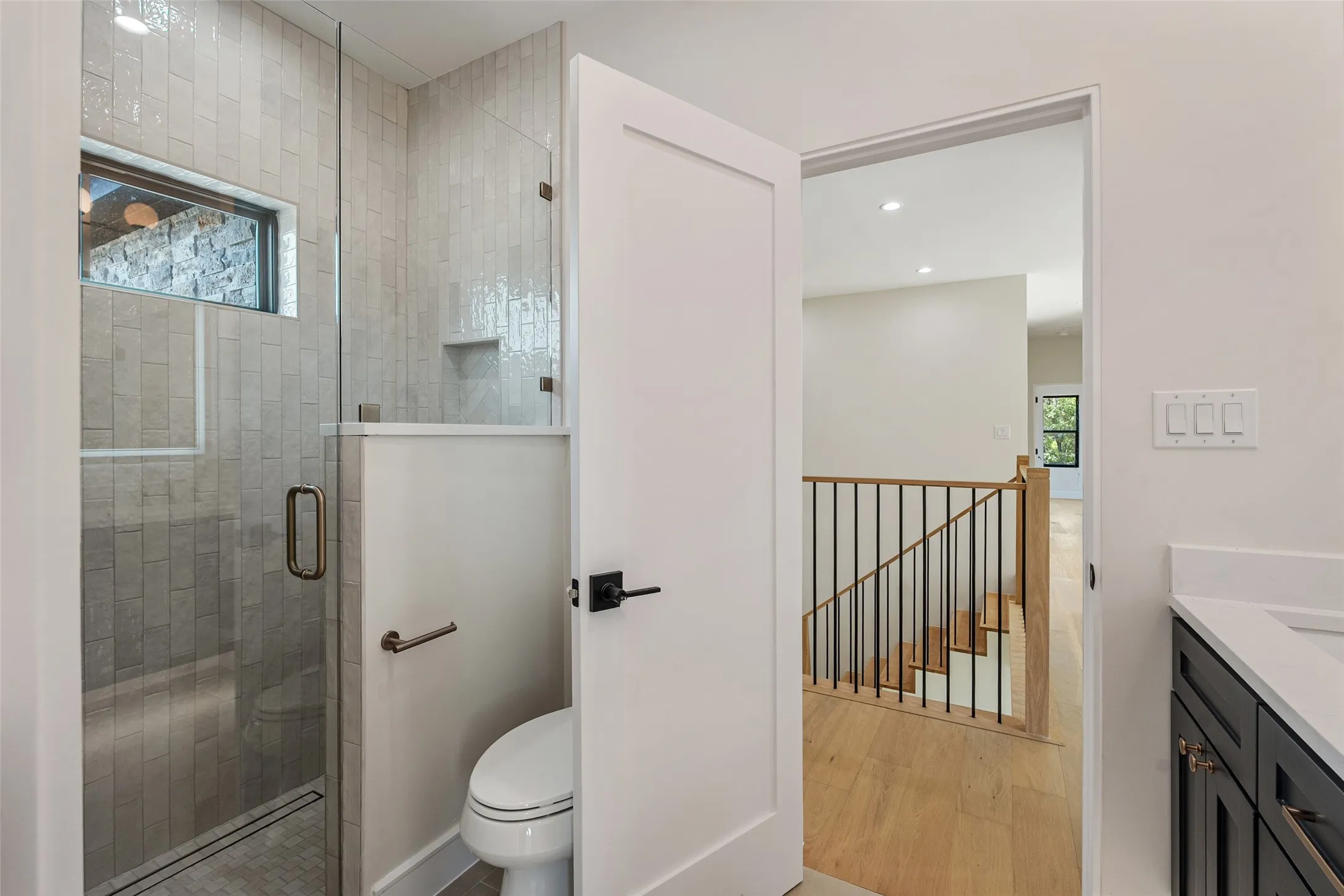 Glass-enclosed shower with vertical tile detailing and built-in niche