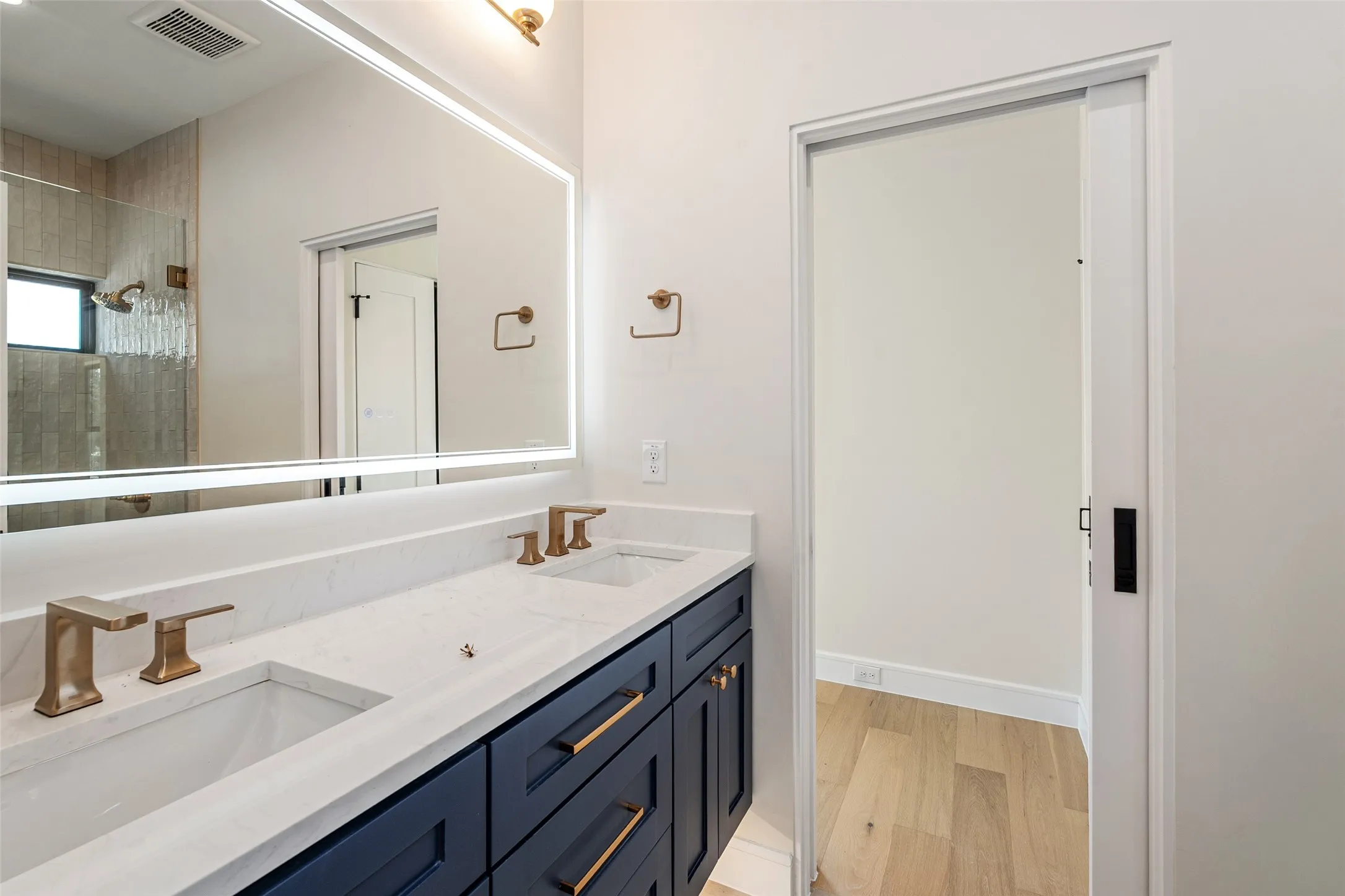 Double vanity with white countertop, dual undermount sinks, and bronze-finish faucets