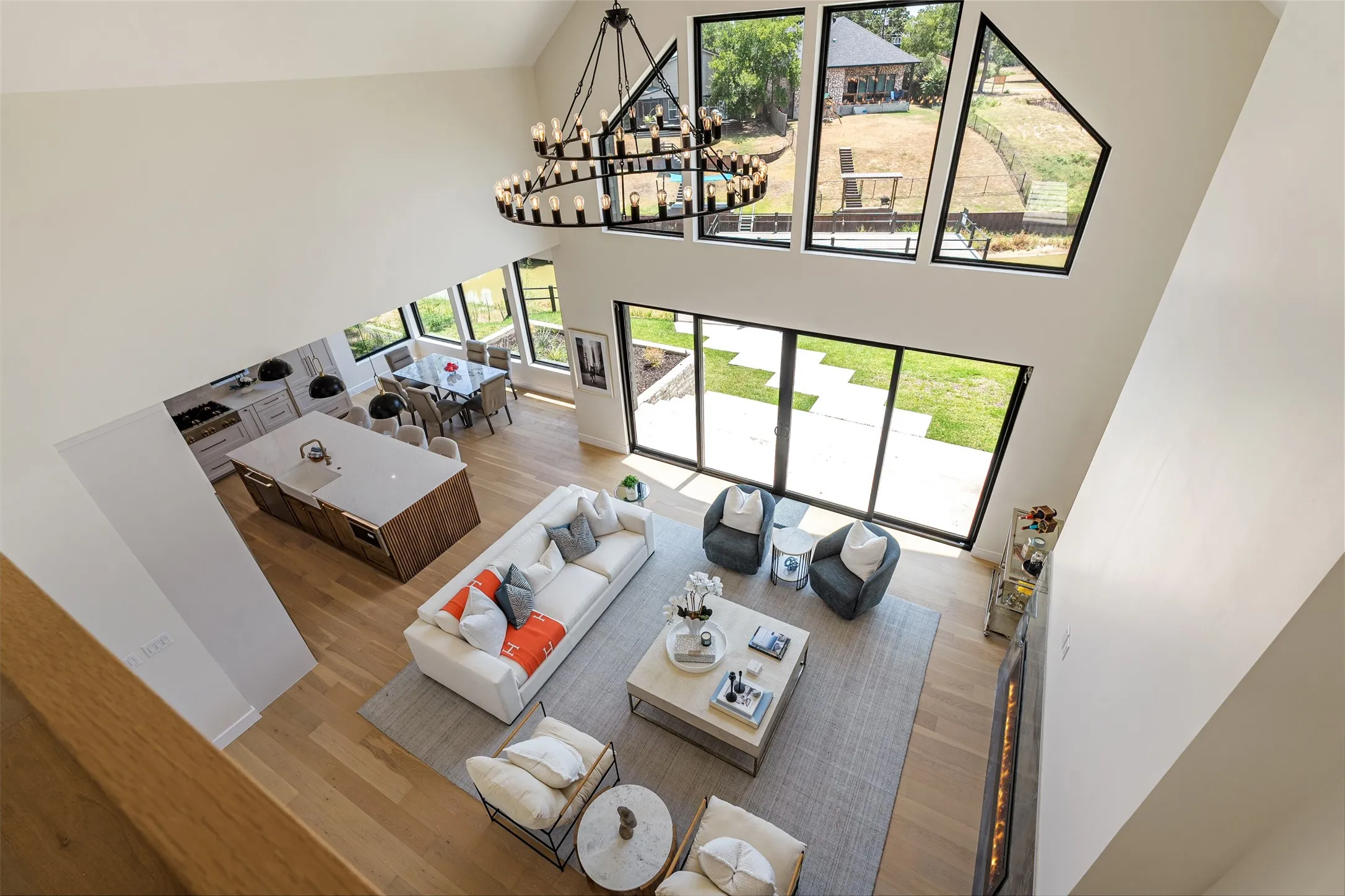 Two-story ceiling with a contemporary chandelier, hardwood flooring, and large windows