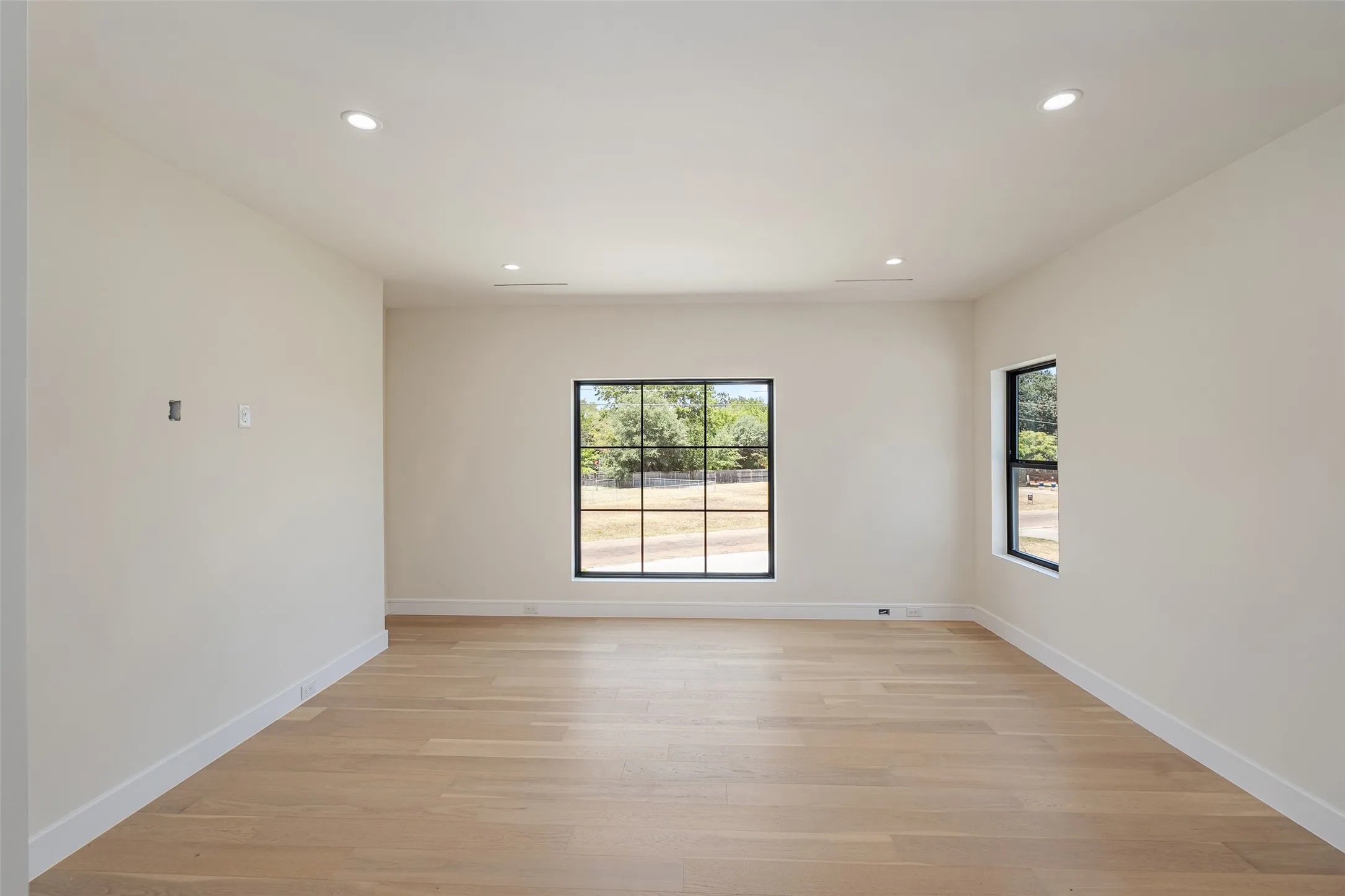 Hardwood-finish flooring, recessed ceiling lighting, and black-framed windows