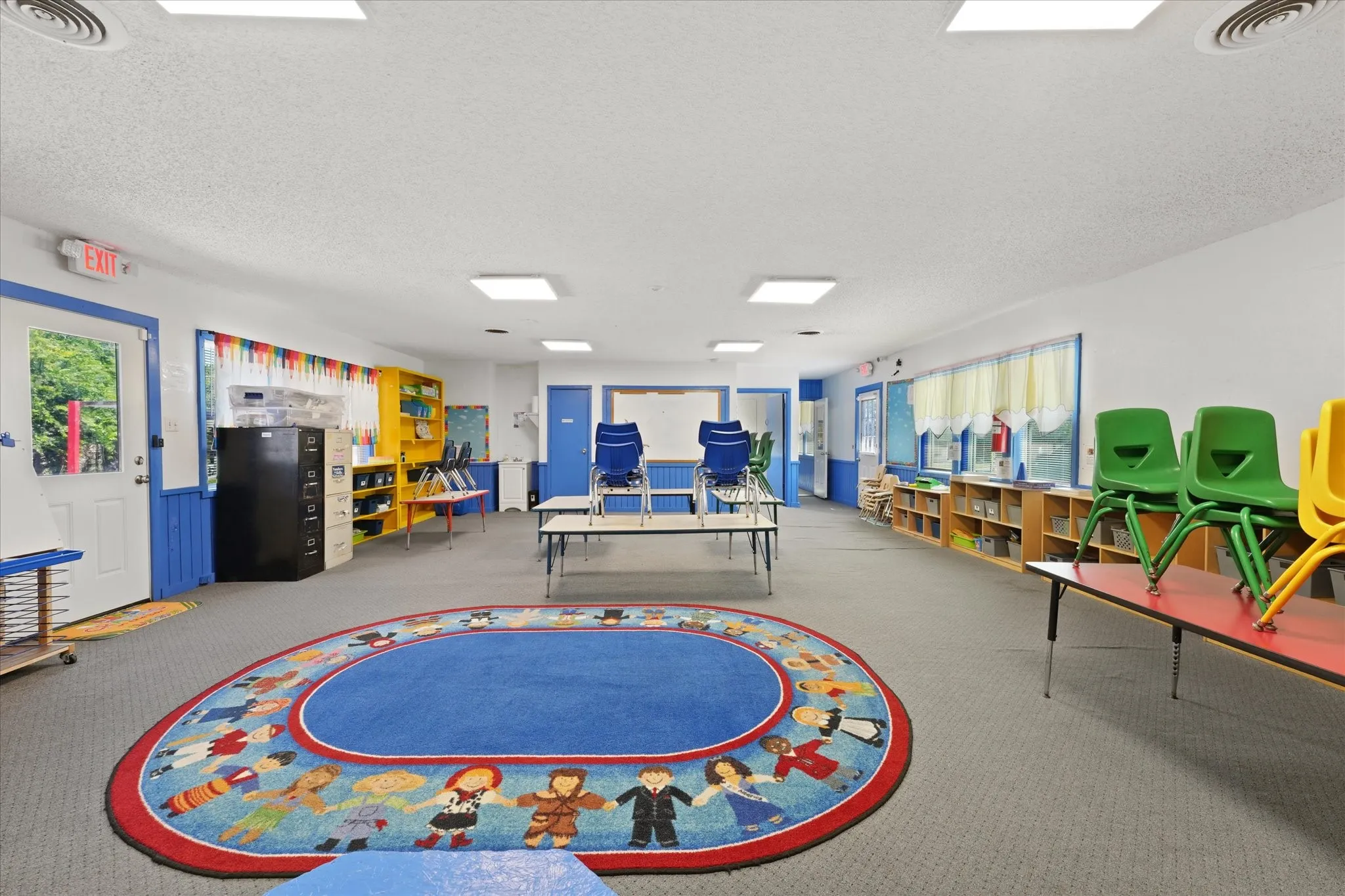 Bright, open learning environment featuring durable carpet flooring, recessed ceiling lighting, and abundant natural light from overhead skylights