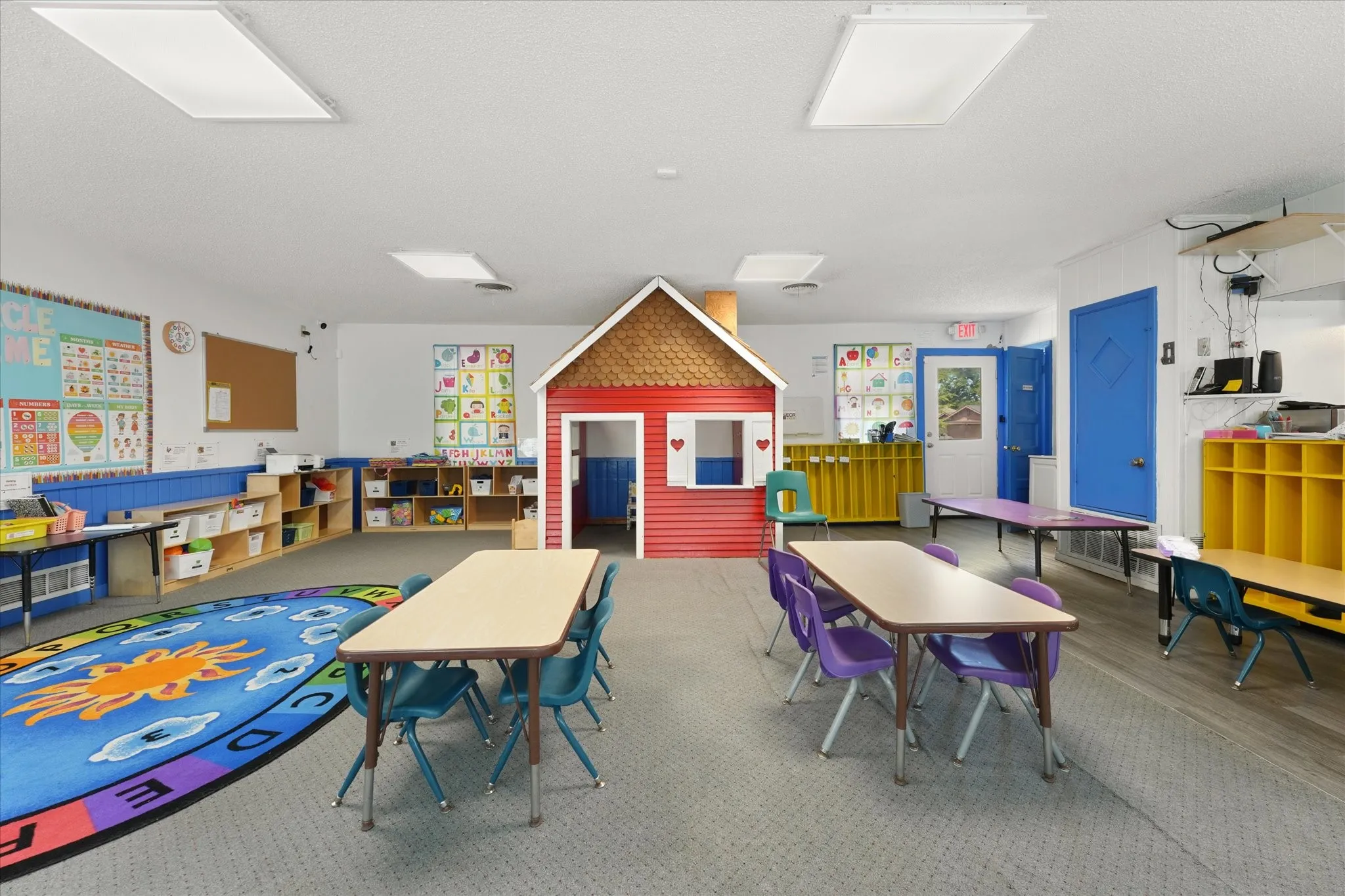 Spacious room featuring a playhouse structure, integrated shelving, ample overhead lighting, and two entry doors