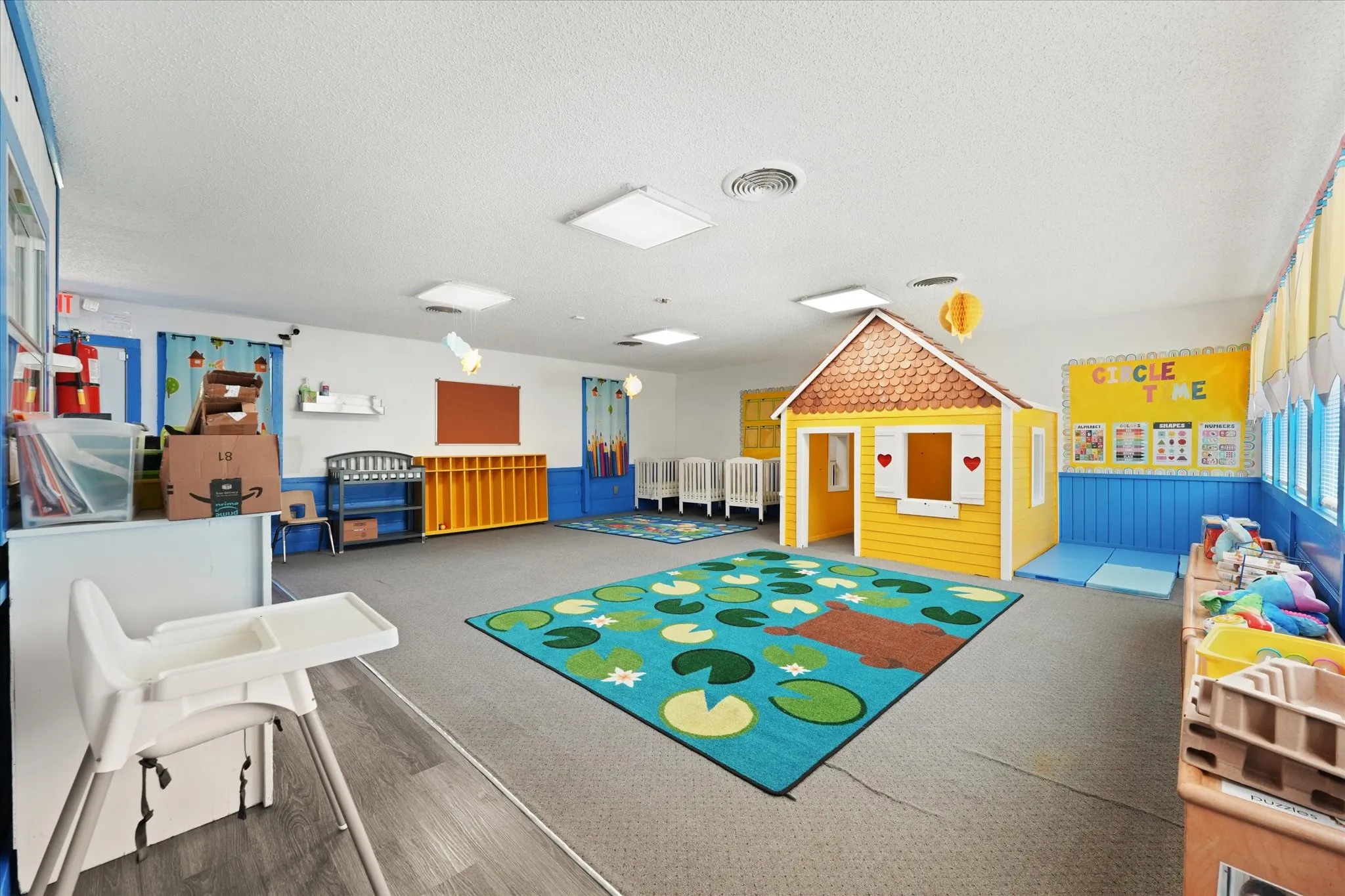 Bright, open learning environment featuring durable polished concrete flooring, recessed and panel ceiling lighting, and colorful interactive play zones