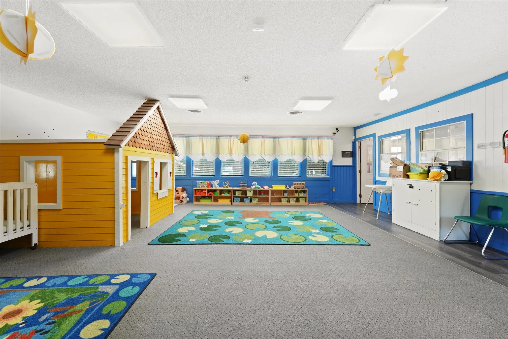 Spacious room featuring a built-in playhouse, multiple windows, recessed lighting, and mixed flooring with carpet and wood-finish sections