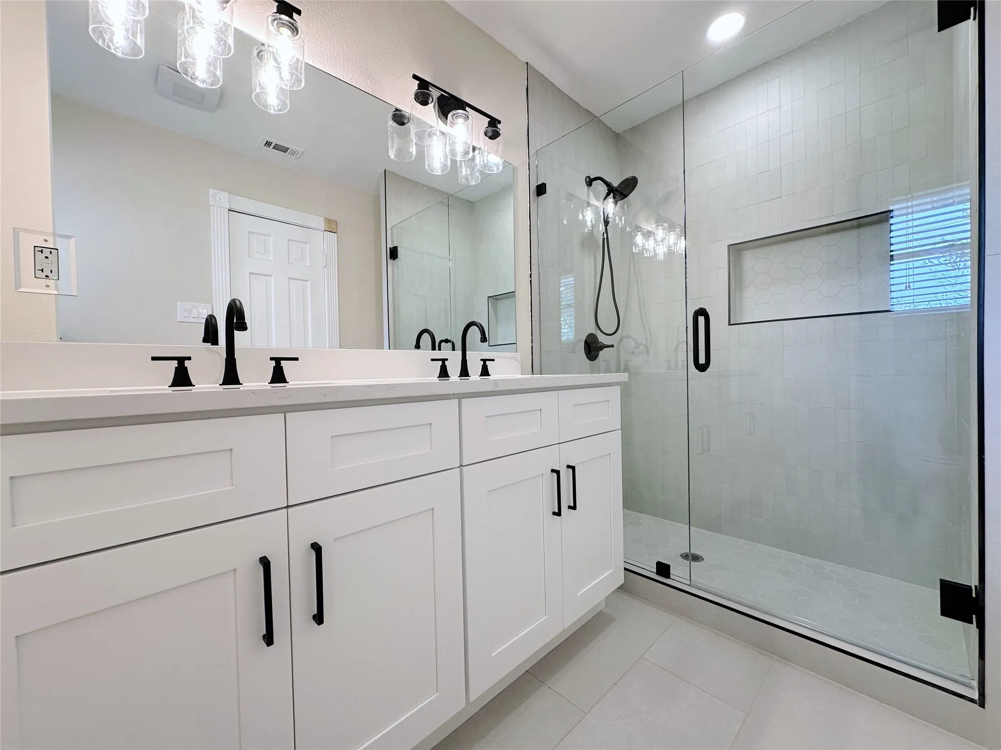 Dual vanity with white cabinetry, matte black hardware, and an expansive mirror