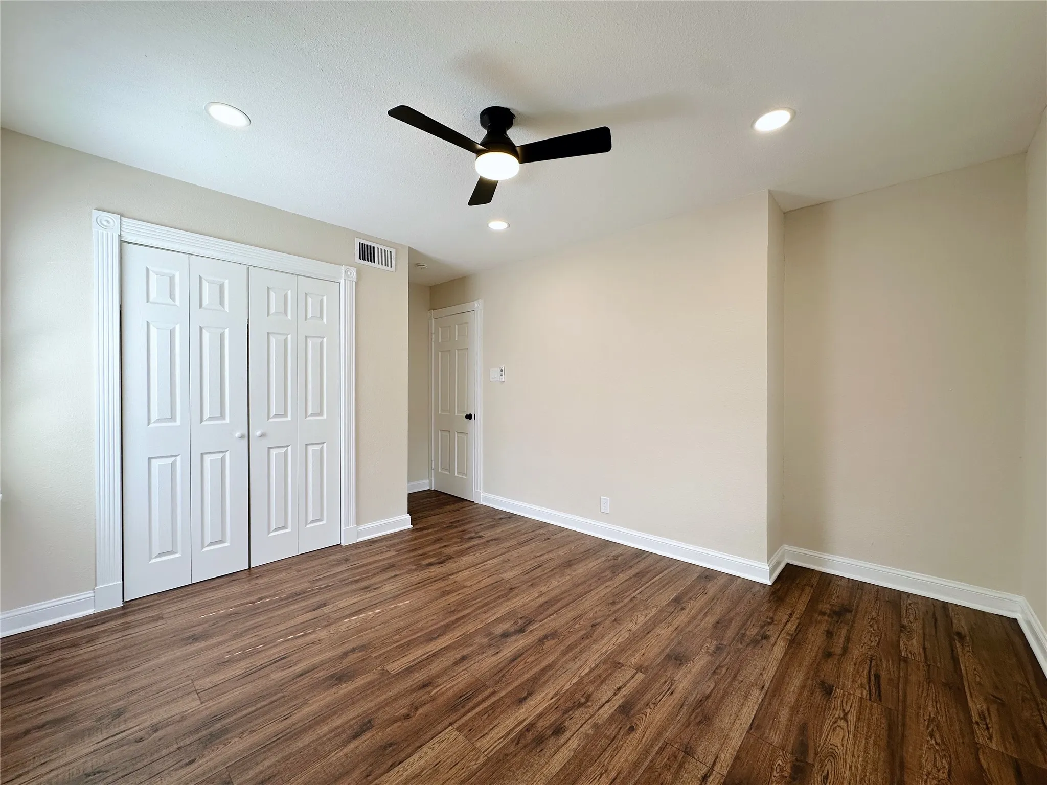 Wood-finish flooring, recessed lighting, ceiling fan with light, bi-fold closet doors, and neutral wall tones