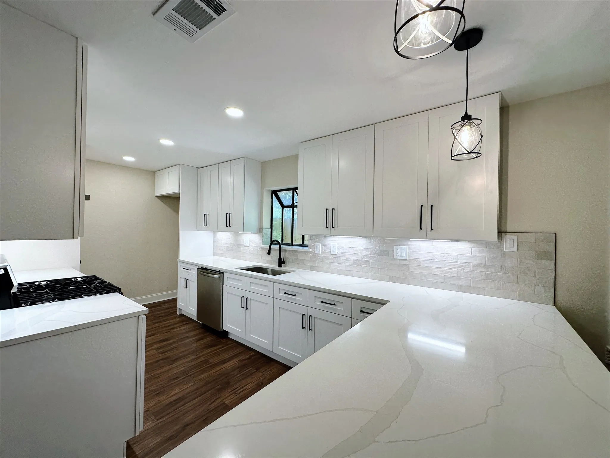 Kitchen featuring white cabinetry, quartz countertops, stainless steel appliances, wood-finish flooring, and pendant lighting