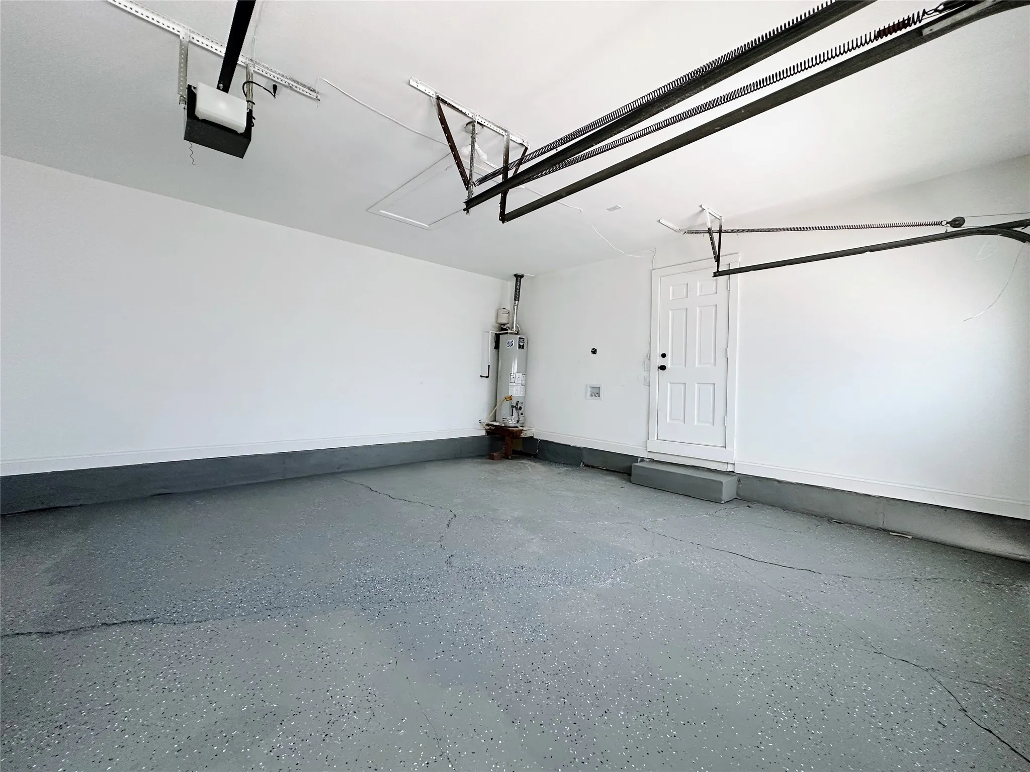 Garage with speckled epoxy flooring, white painted walls, and a four-panel interior door