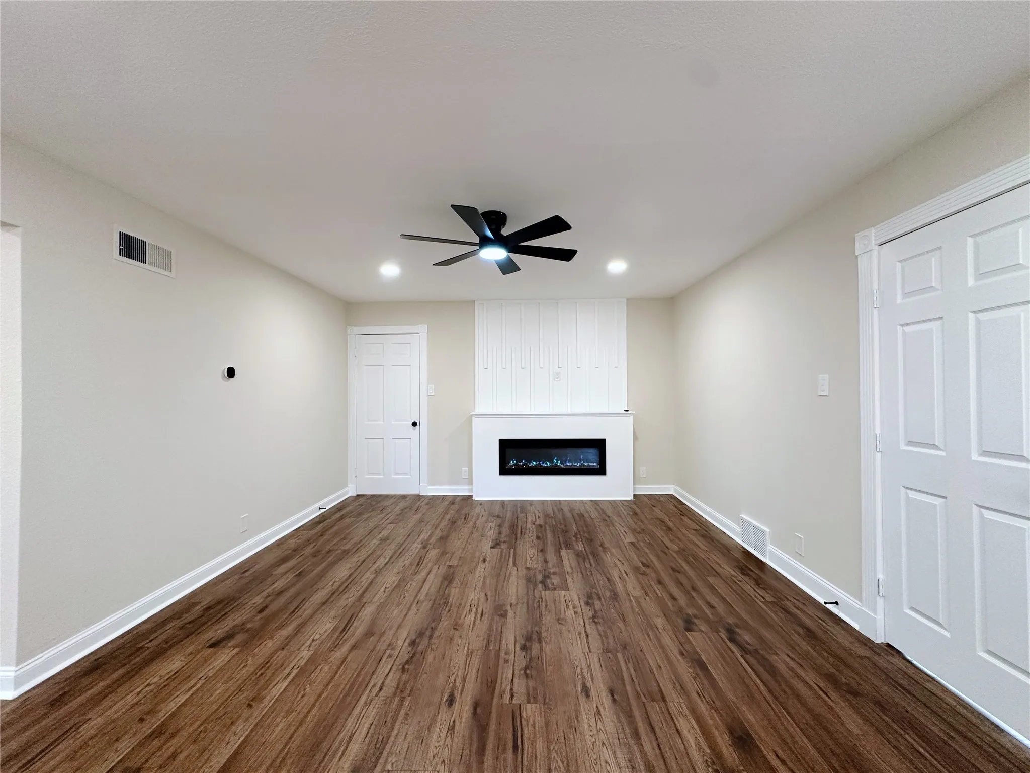 Wood-finish flooring, recessed lighting, ceiling fan, decorative fireplace with mantle, and paneled doors