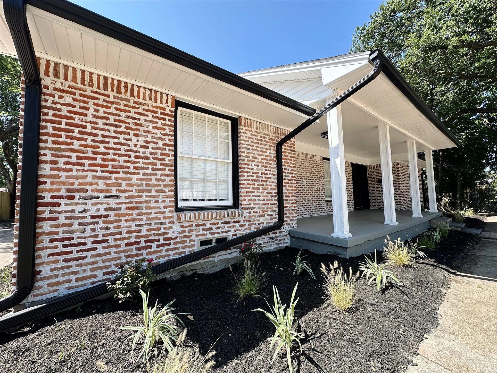 Brick exterior with a covered porch featuring white columns