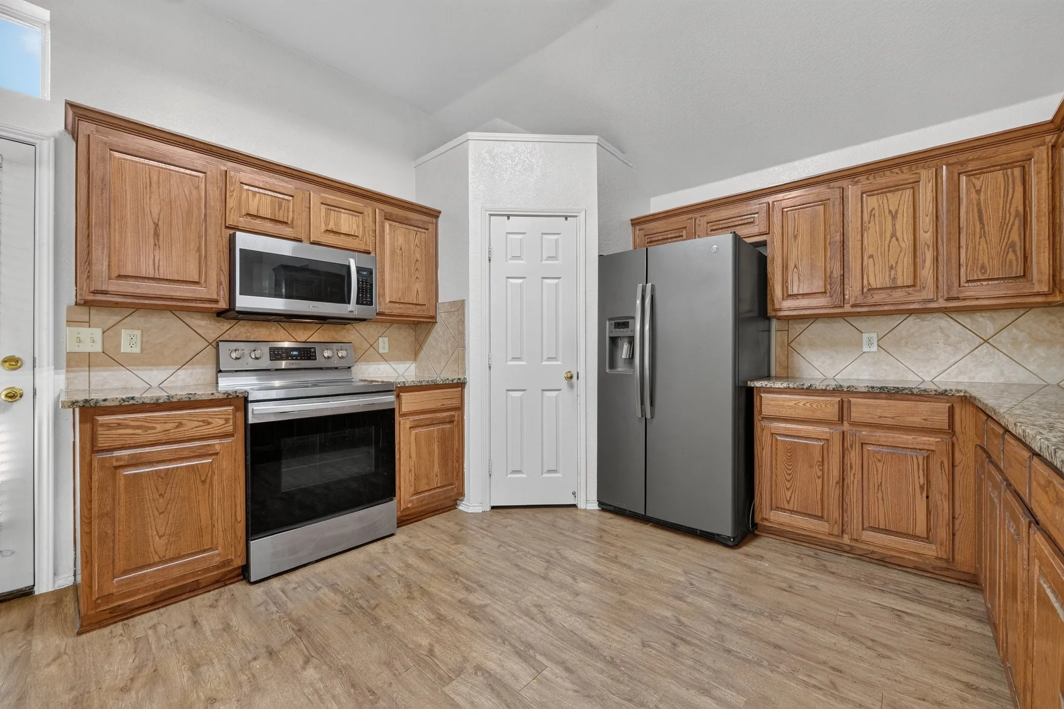 Kitchen featuring wood-finish flooring, wood cabinetry, granite-style countertops, and a tile backsplash