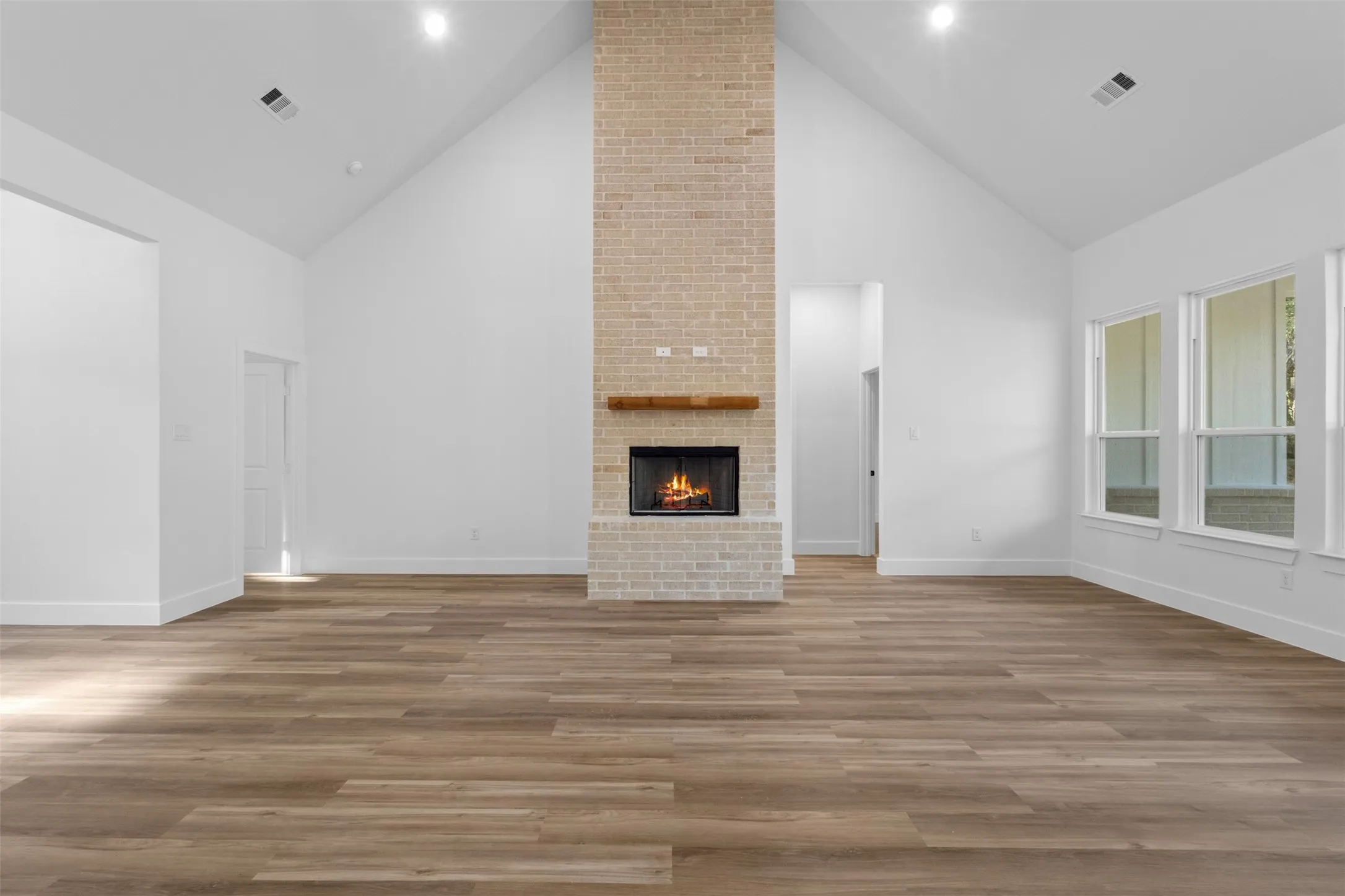 Spacious great room featuring soaring vaulted ceilings, recessed lighting, and wide-plank wood-finish flooring throughout