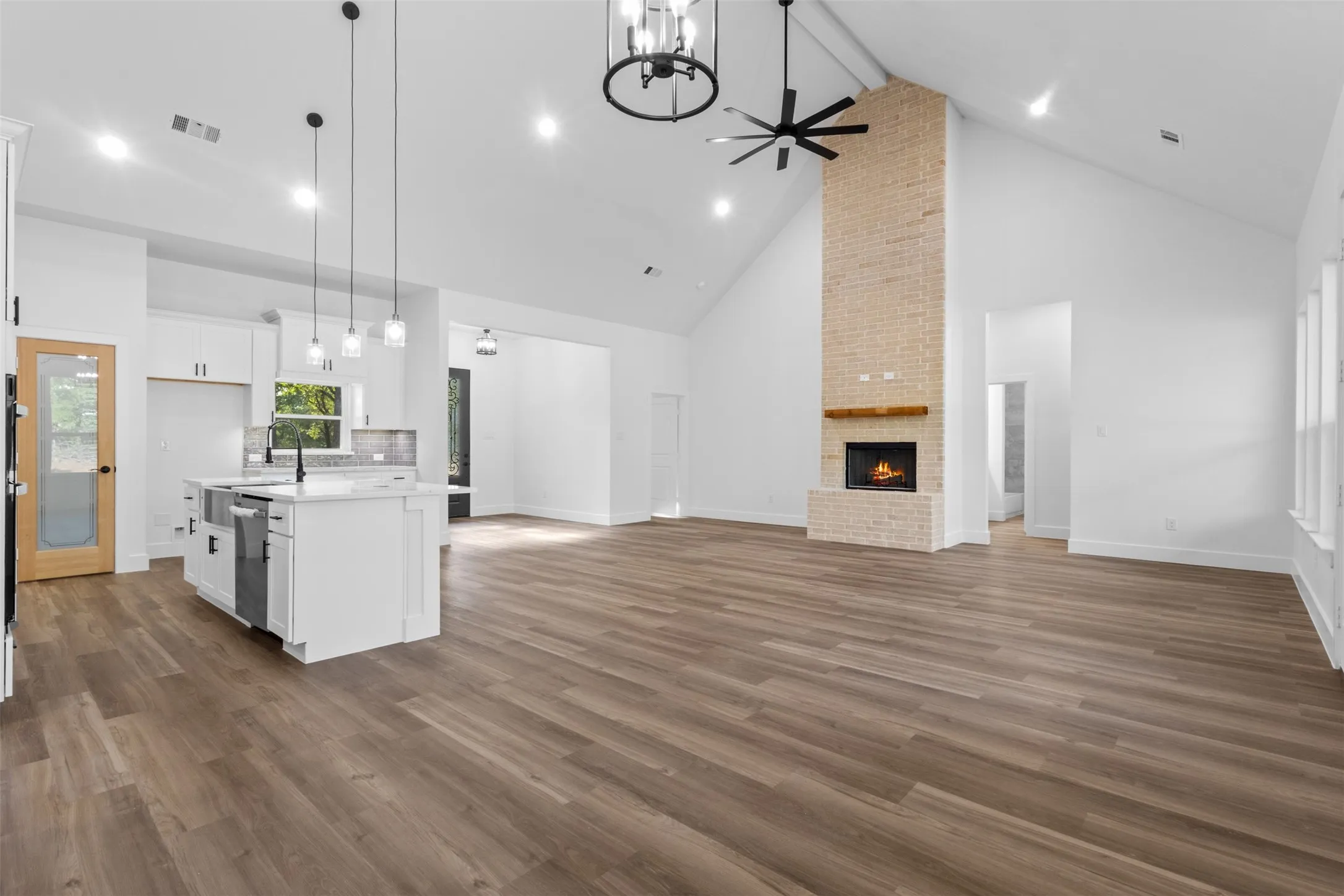 Open-concept living space featuring wide-plank wood-finish flooring, soaring vaulted ceilings with recessed lighting, and a ceiling fan