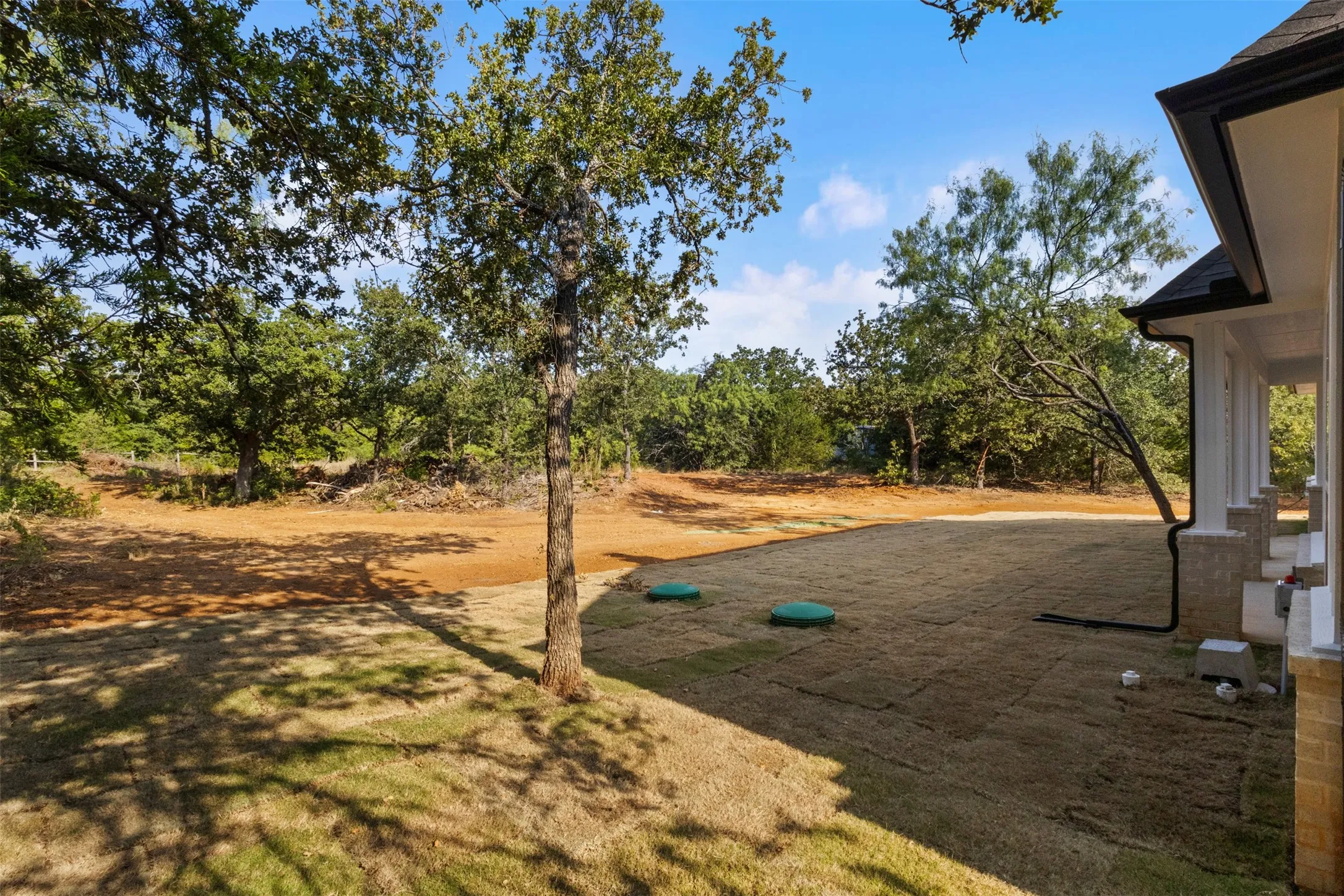 Expansive outdoor living space with mature shade trees, level grounds ideal for recreation or landscaping, and a covered structure providing shelter