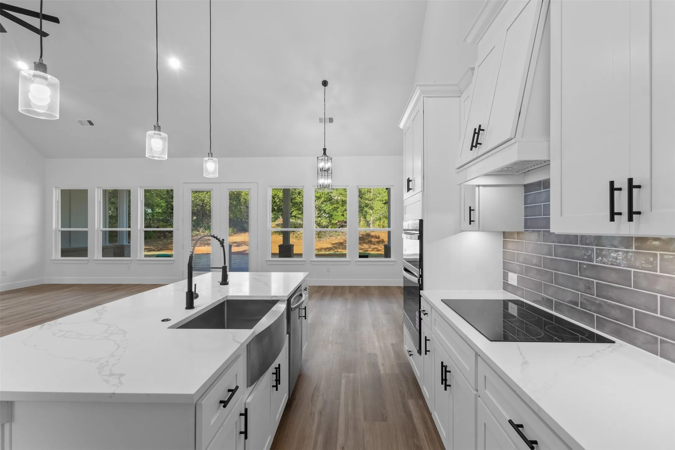 Contemporary kitchen featuring white cabinetry with matte black hardware, white quartz countertops, and a stainless steel apron-front sink
