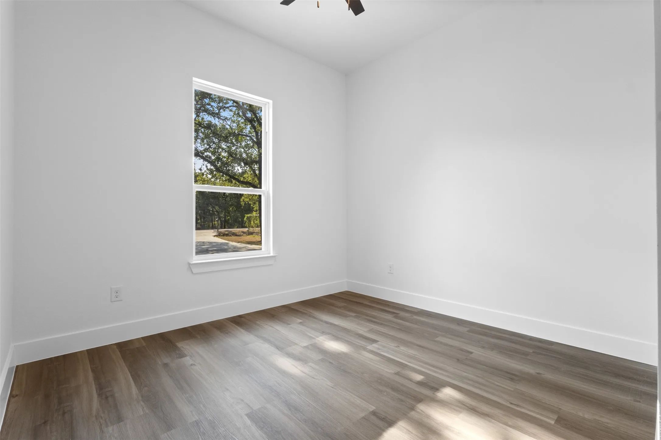 Wood-finish flooring, white walls, and a large window with natural light