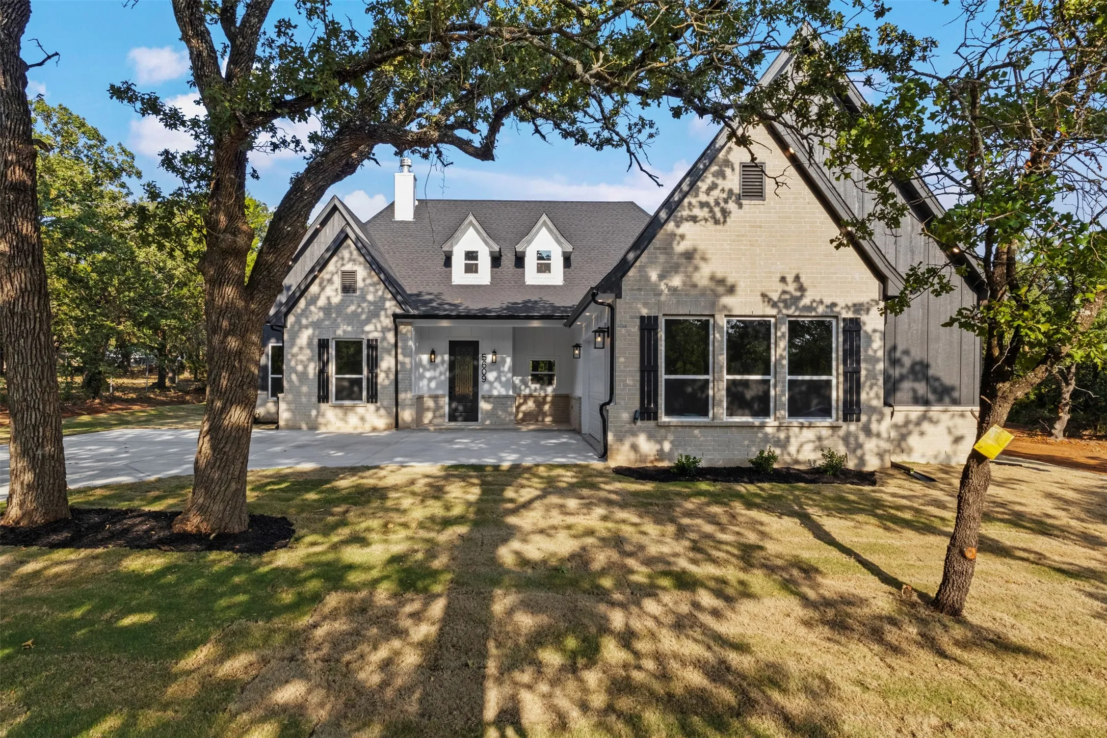 Modern farmhouse residence showcasing a light stone and siding exterior with peaked gable rooflines and dormer windows